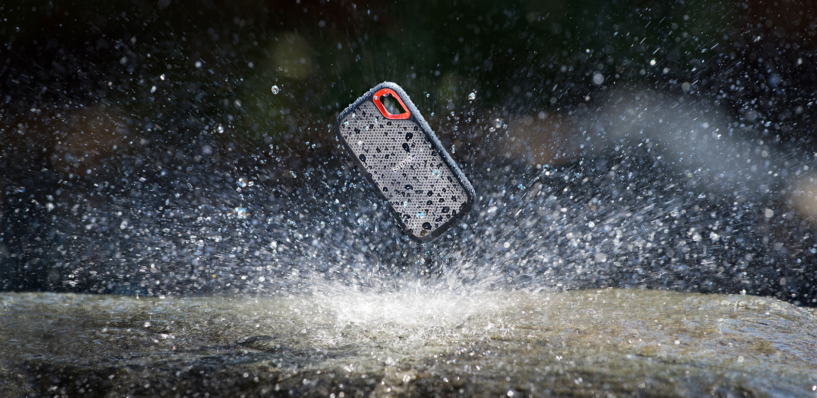 Una custodia per telefono con goccioline d'acqua, sospesa sopra una superficie bagnata, circondata da spruzzi d'acqua. Sfondo scuro.