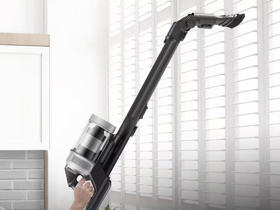 Osoba odkurzająca żaluzję. Odkurzacz trzymany jest pod dużym kątem.