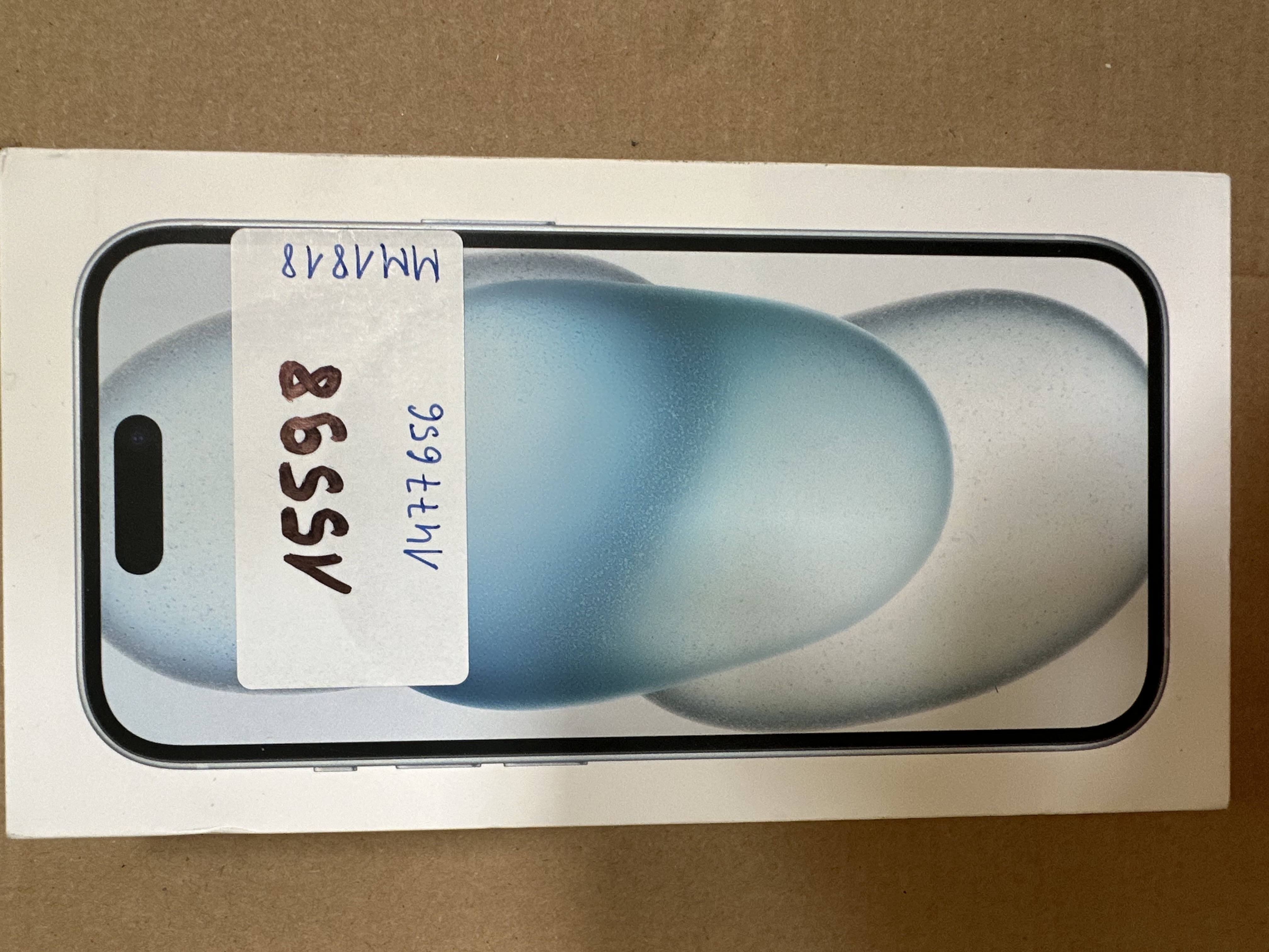 iPhone w pudełku. Pokazuje ekran telefonu. Widoczna etykieta z numerami.