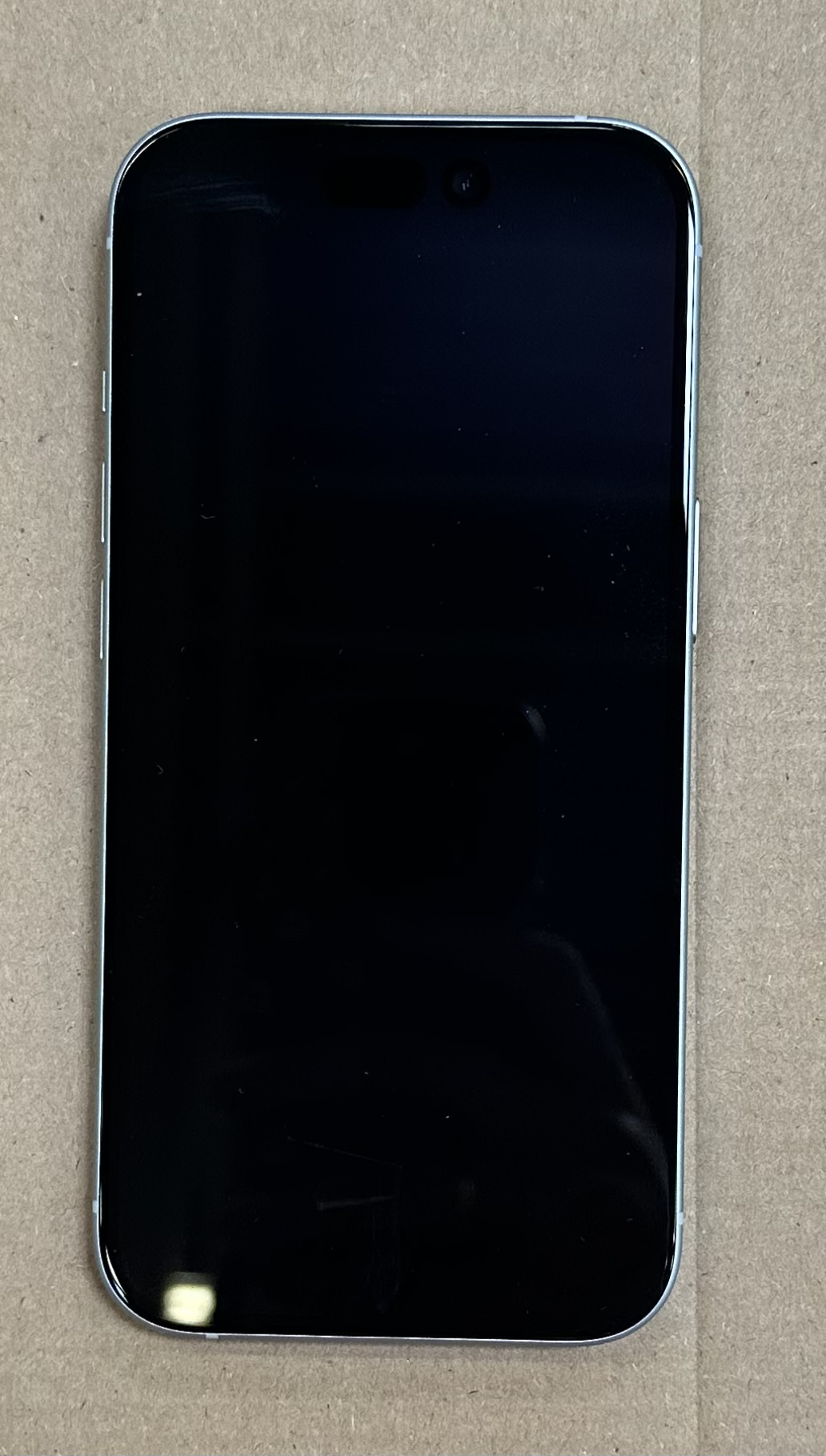 Ekran iPhone'a, całkowicie czarny, w pudełku. Widoczna srebrna ramka.
