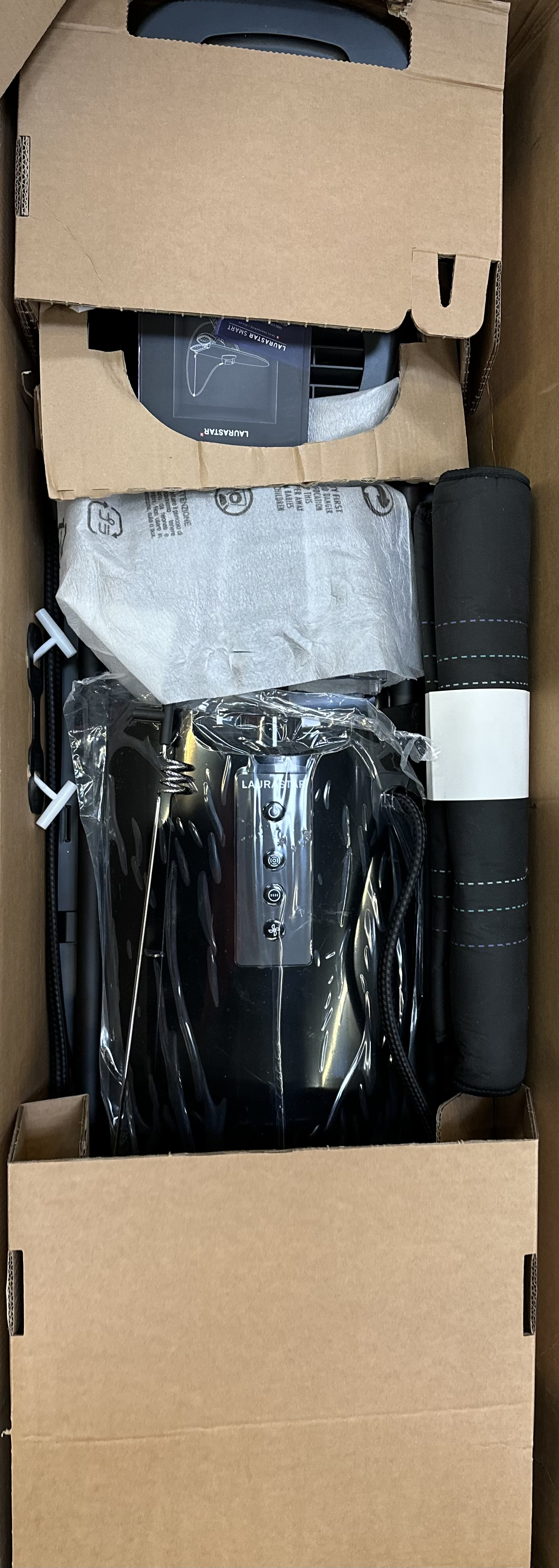 Pudełko z zapakowaną elektroniką. Czarne przedmioty wewnątrz kartonowego pudełka.