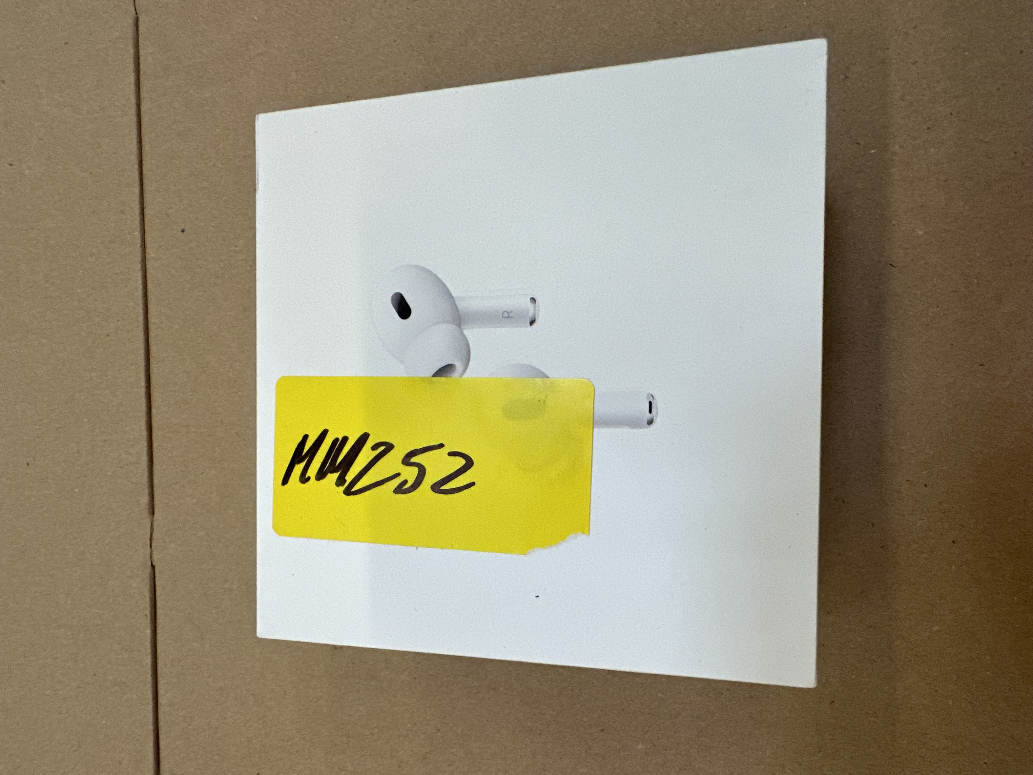 Białe pudełko AirPods Pro z AirPods i żółtą naklejką z napisem MH252.