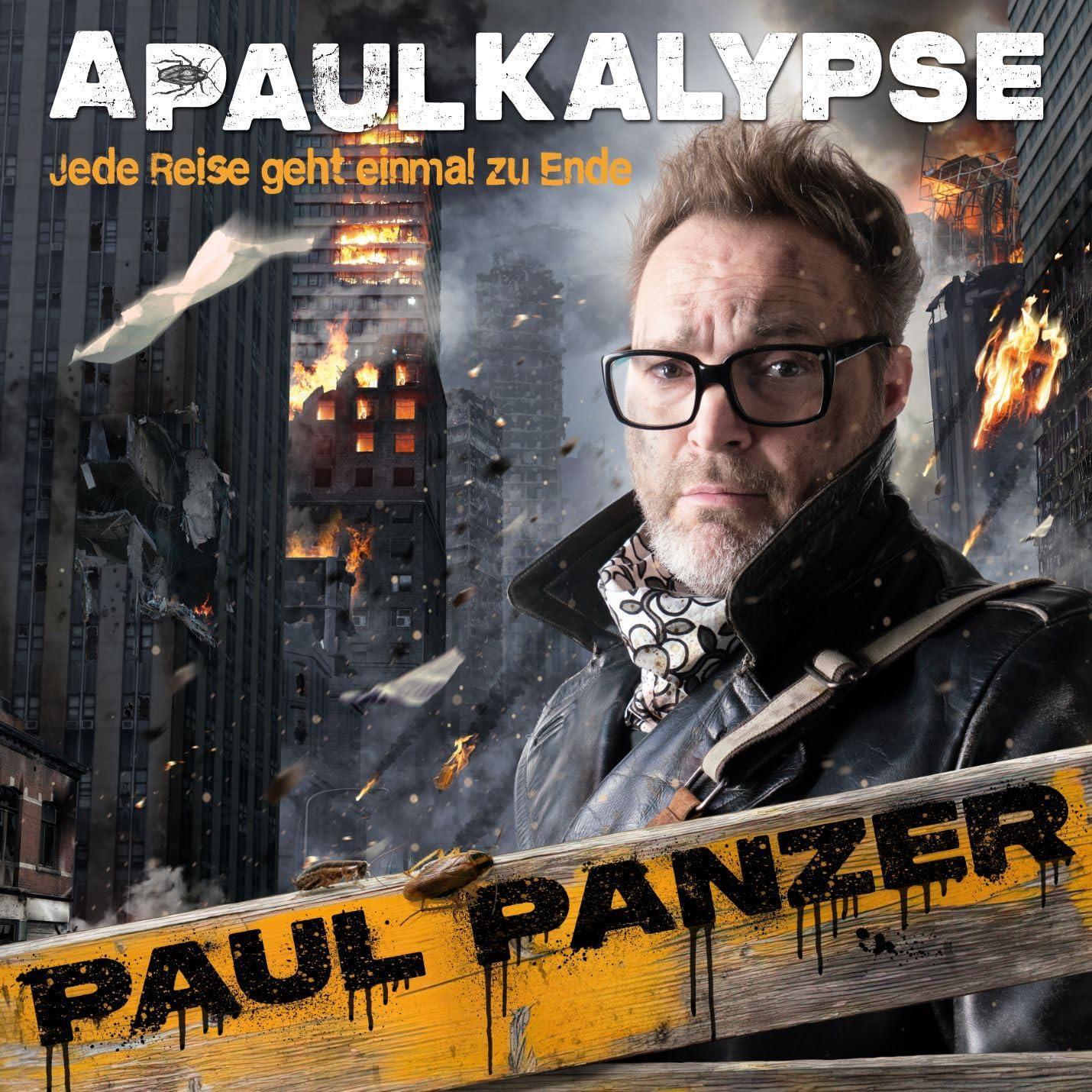 Mann mit Brille, Stadt im Hintergrund zerstört. Auf dem Bild steht APAULKALYPSE und PAUL PANZER.