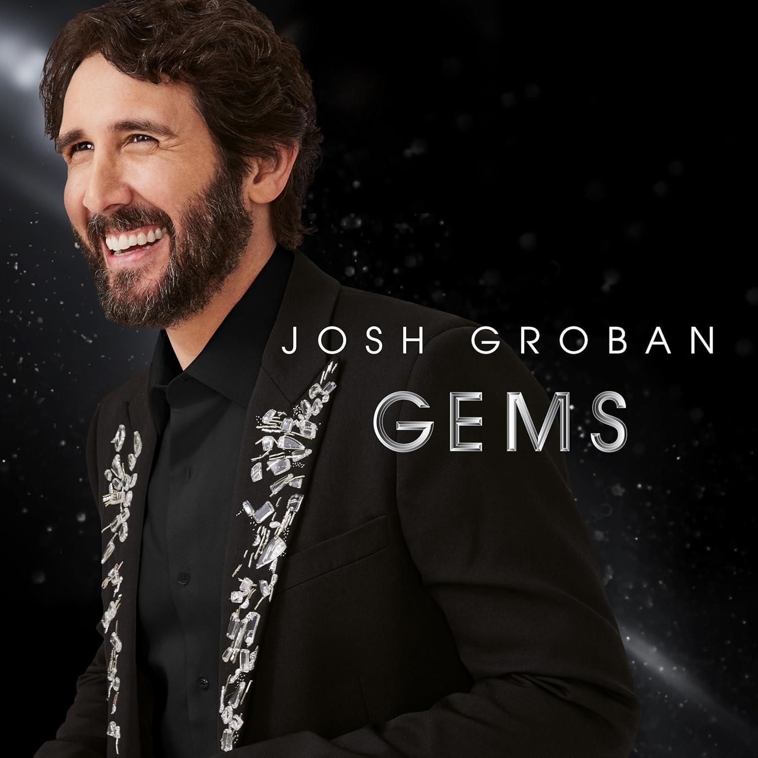 Mann in einem schwarzen Anzug, der lächelt. Der Text auf dem Bild lautet JOSH GROBAN GEMS.