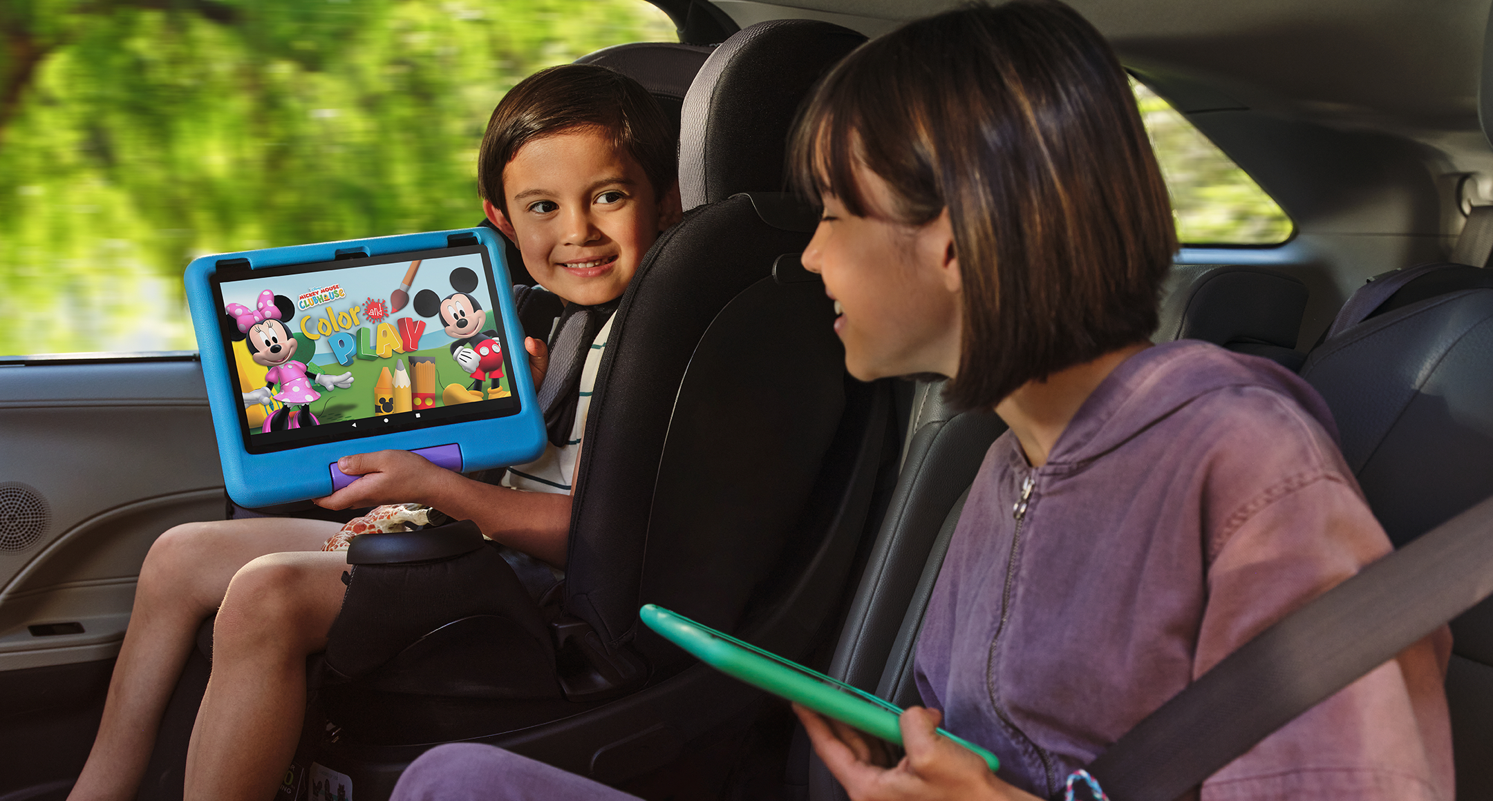 Zwei Kinder in einem Auto. Einer hält ein Tablet mit einem Cartoon mit Minnie Maus.
