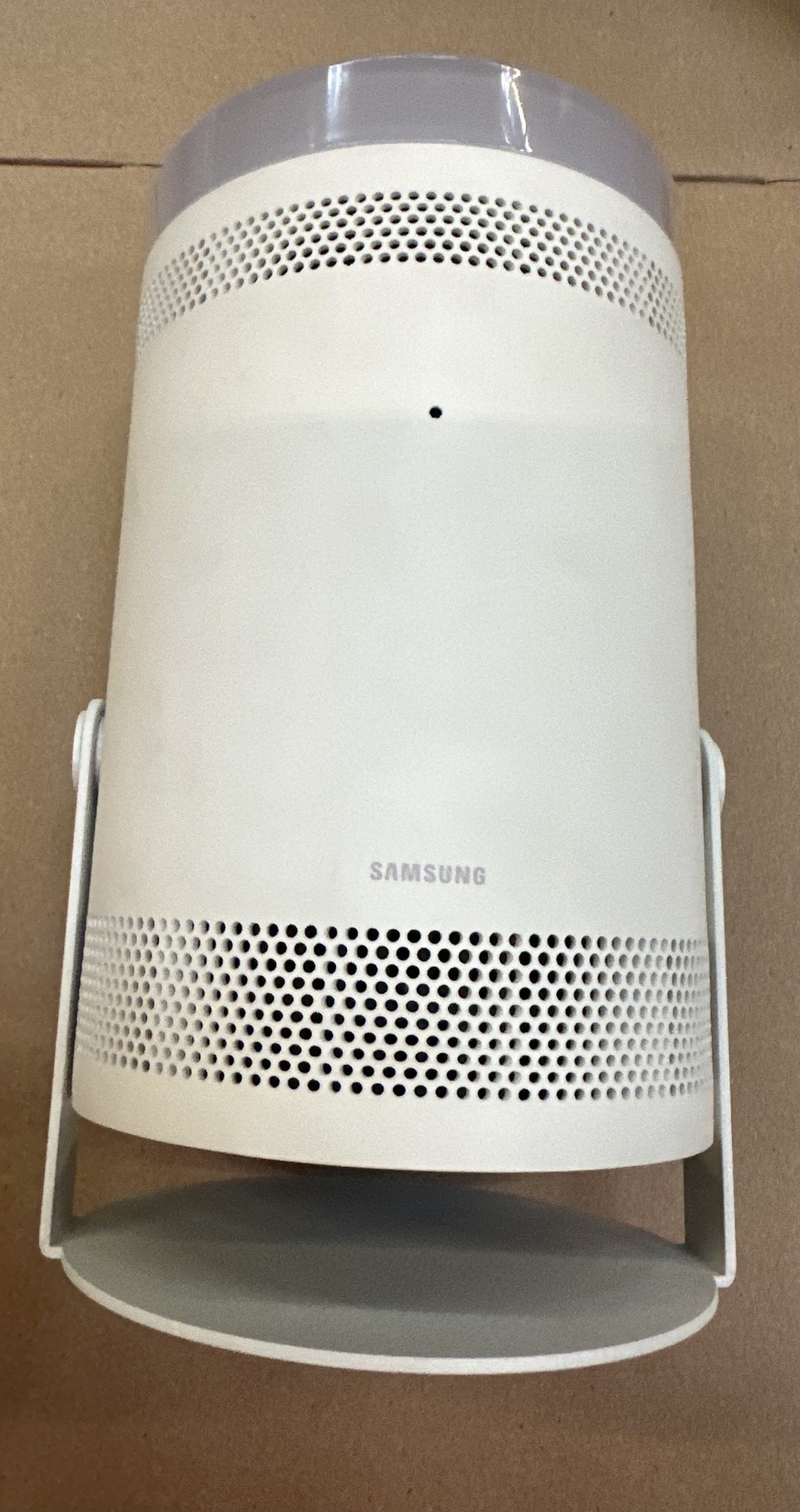 Biały projektor z szarą górą i srebrnym stojakiem. Brązowe tło.