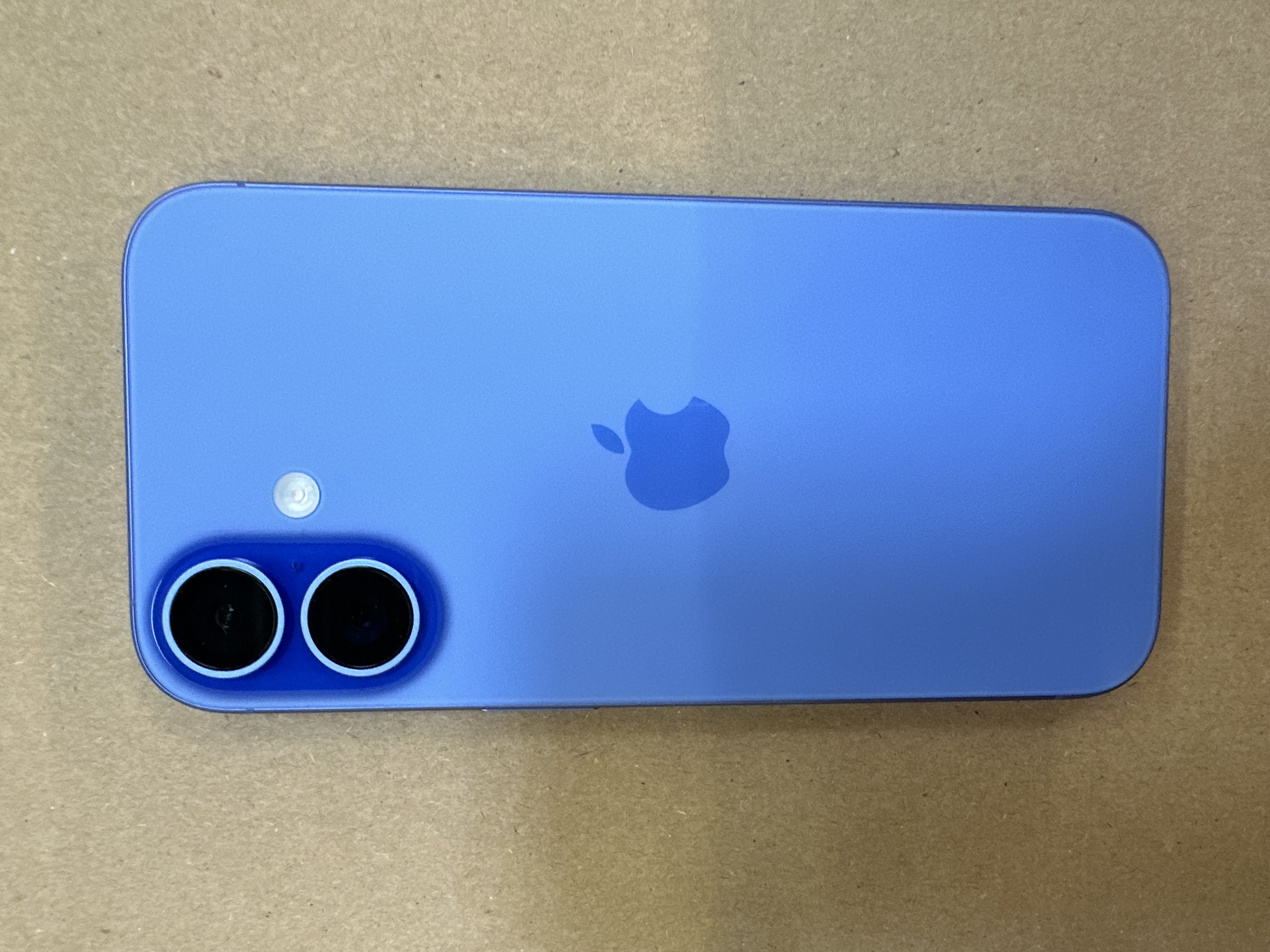 Niebieski iPhone 12, widok z tyłu, pokazujący moduł aparatu, logo Apple i lampę błyskową.