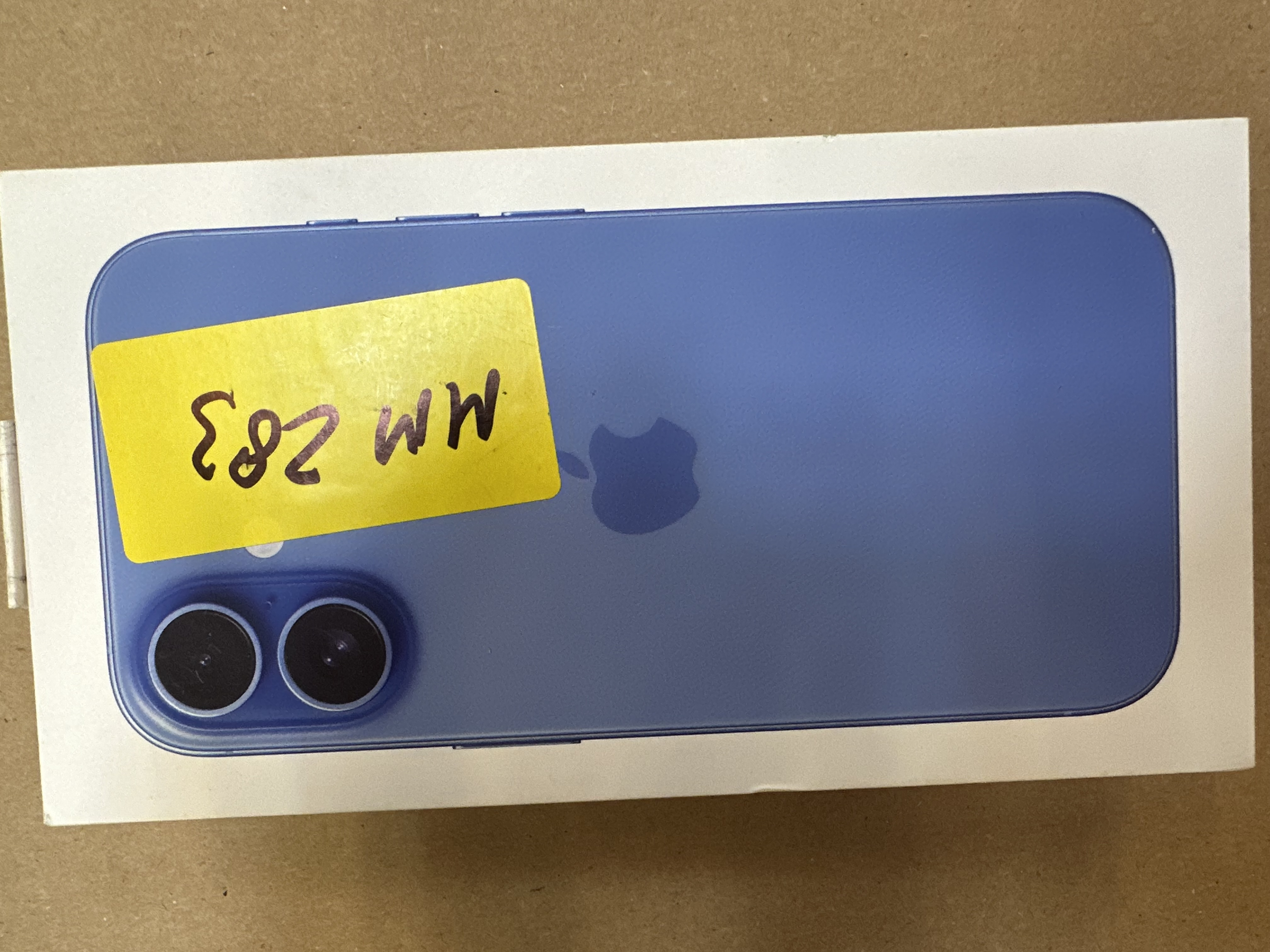 Niebieski iPhone 12 w pudełku, widok z tyłu, z żółtą naklejką z numerem IMEI.
