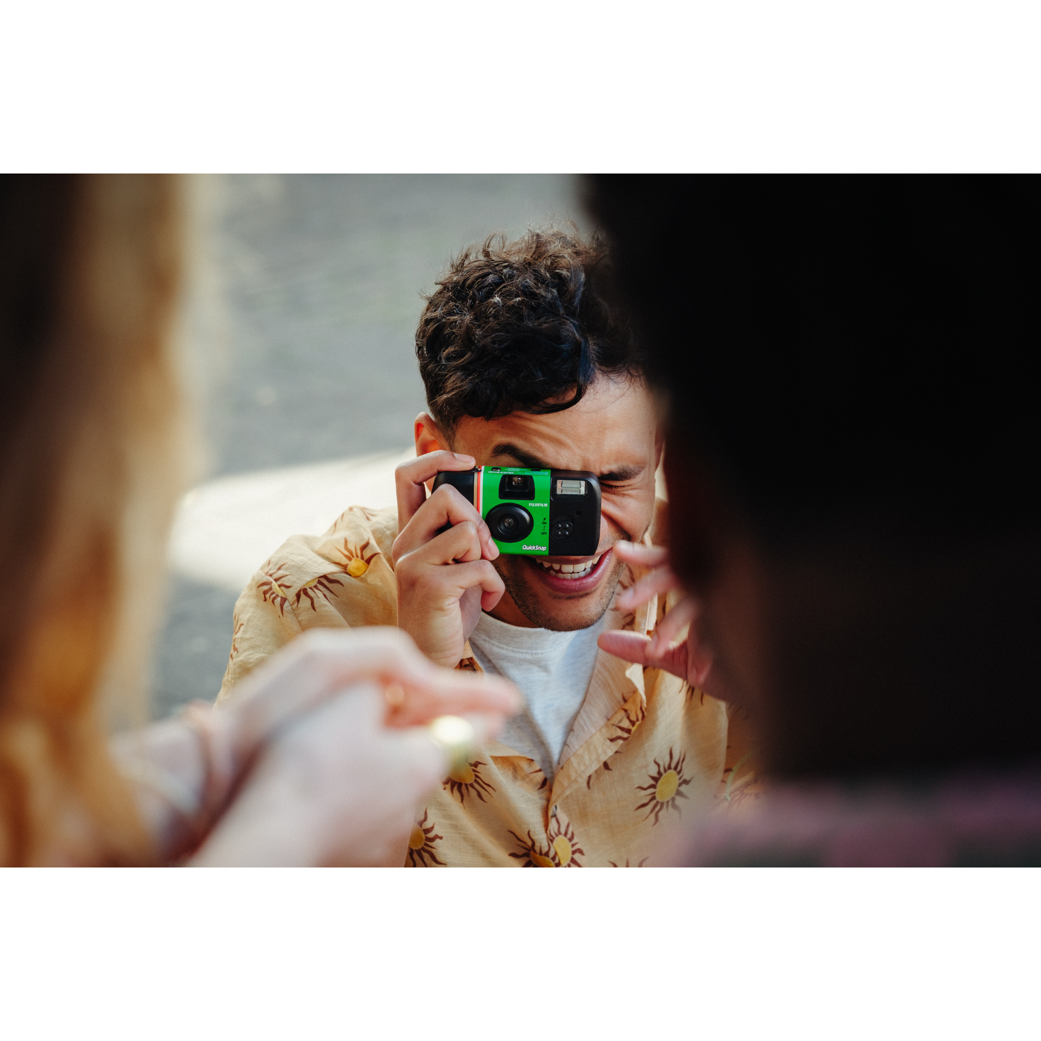 Homme prenant photo avec un appareil QuickSnap, une autre personne au premier plan.