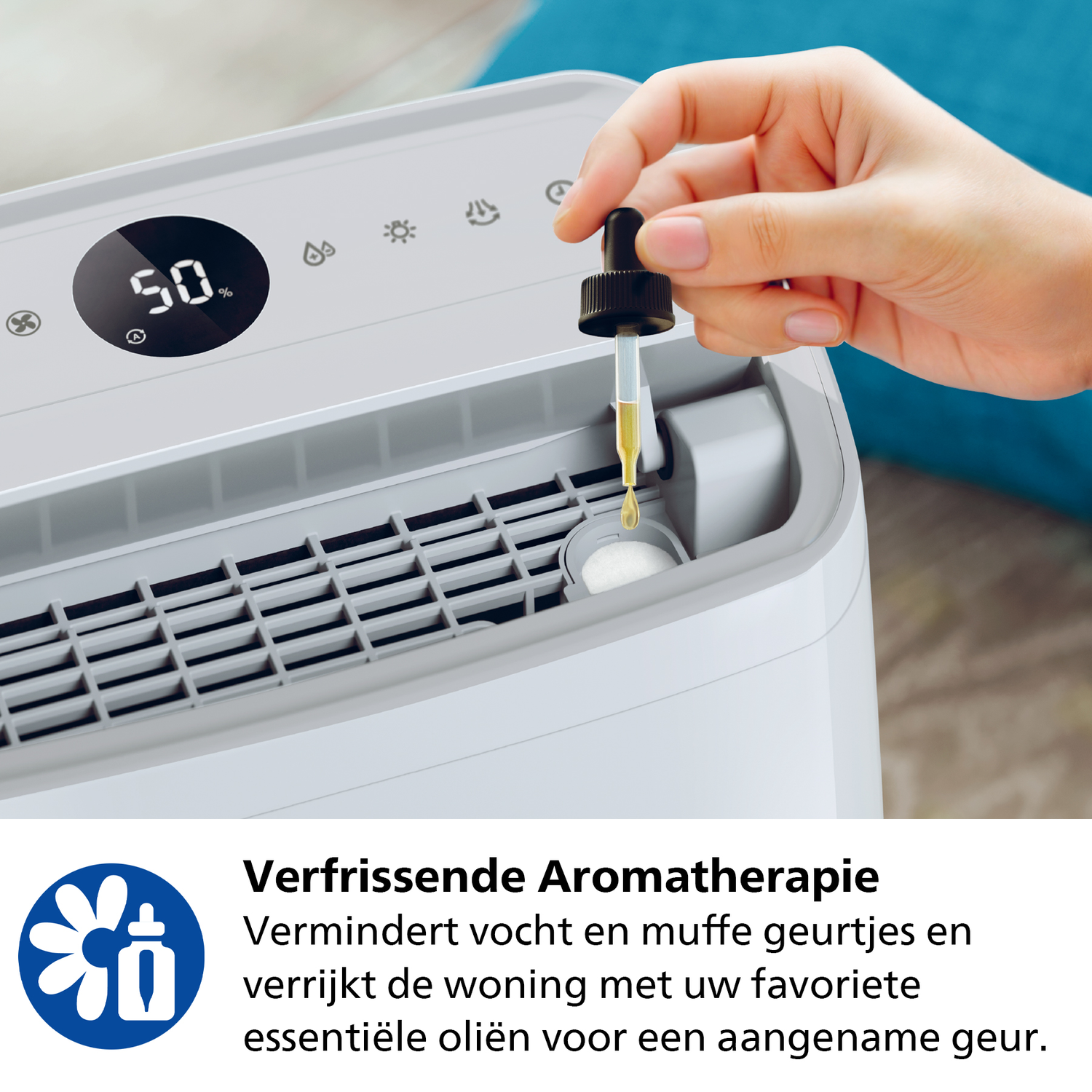 Hand adding oil drops to a white dehumidifier. Top display shows 50% humidity.