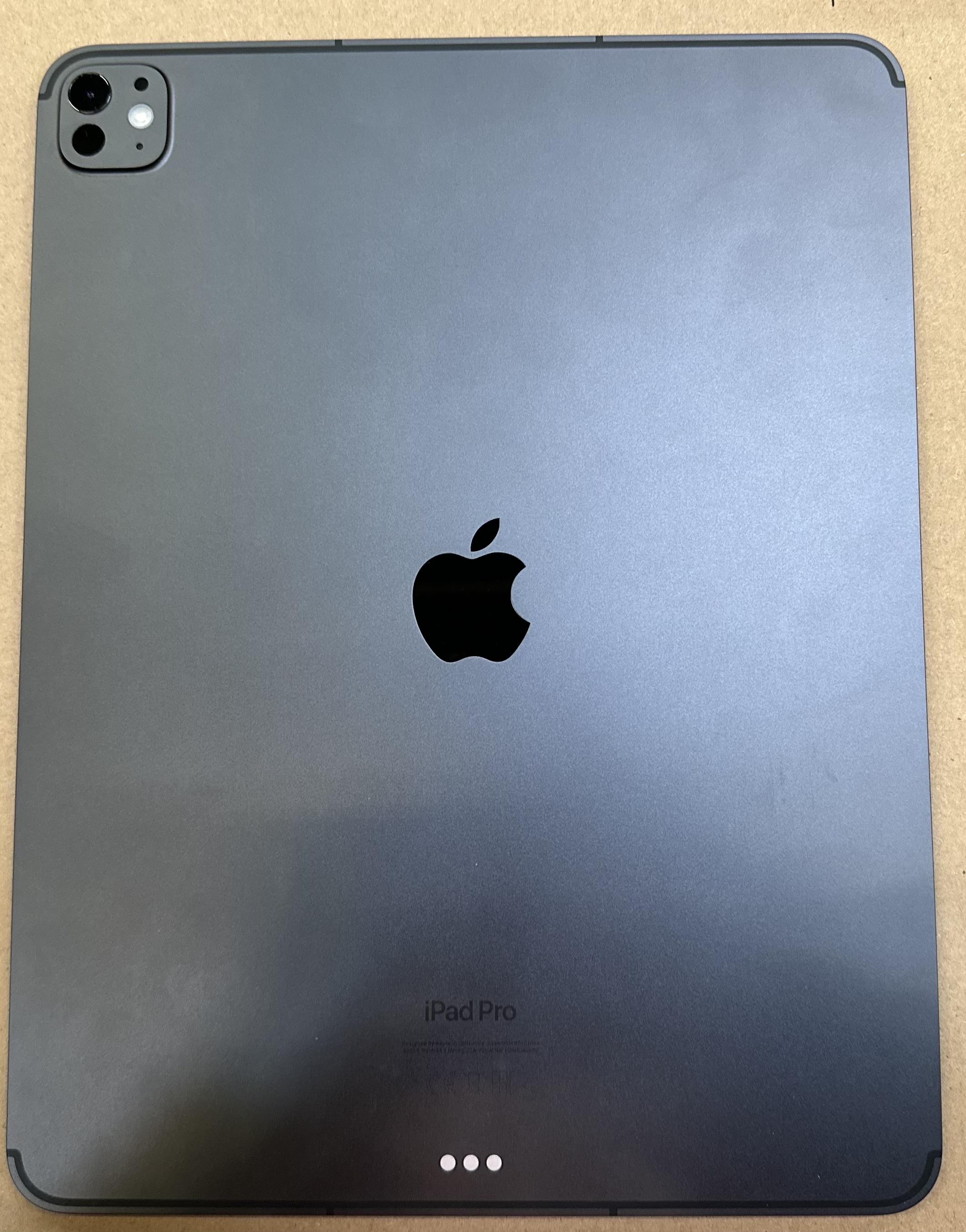 Tył ciemnoszarego iPada Pro z czarnym logo Apple i zestawem kamer.