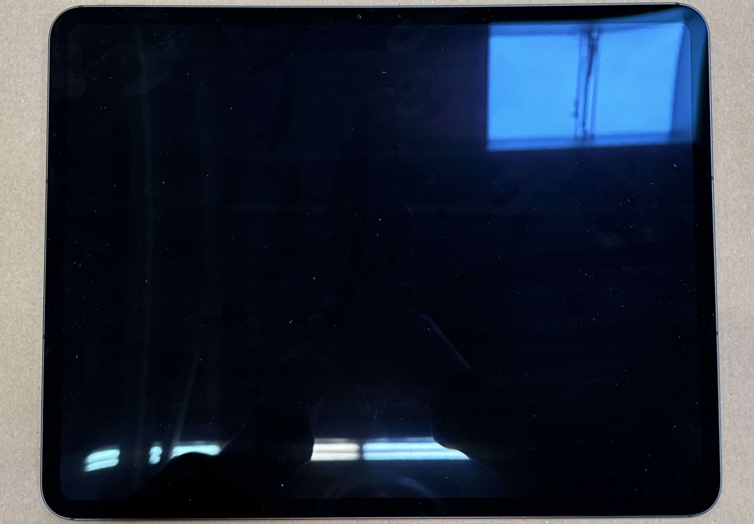 Czarny ekran iPada. Odbicie jasnego okna na górze.