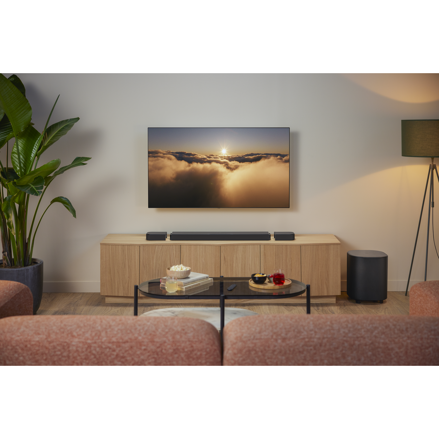 Salon avec TV, coucher de soleil, barre de son JBL, caisson de basses et enceintes.