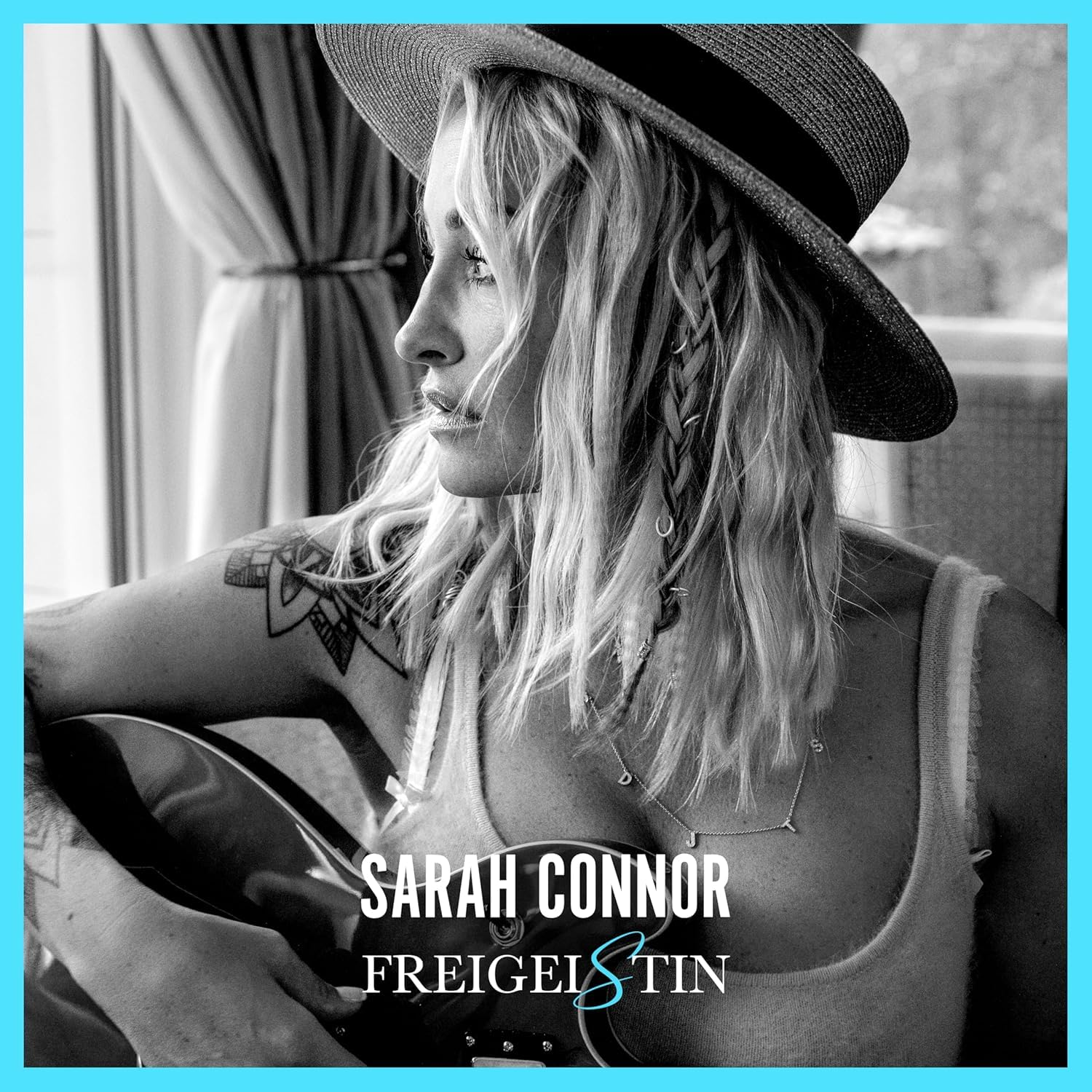 Szöszi nő kalapban, elnéz, gitárt tart. Felirat: 'Sarah Connor'.