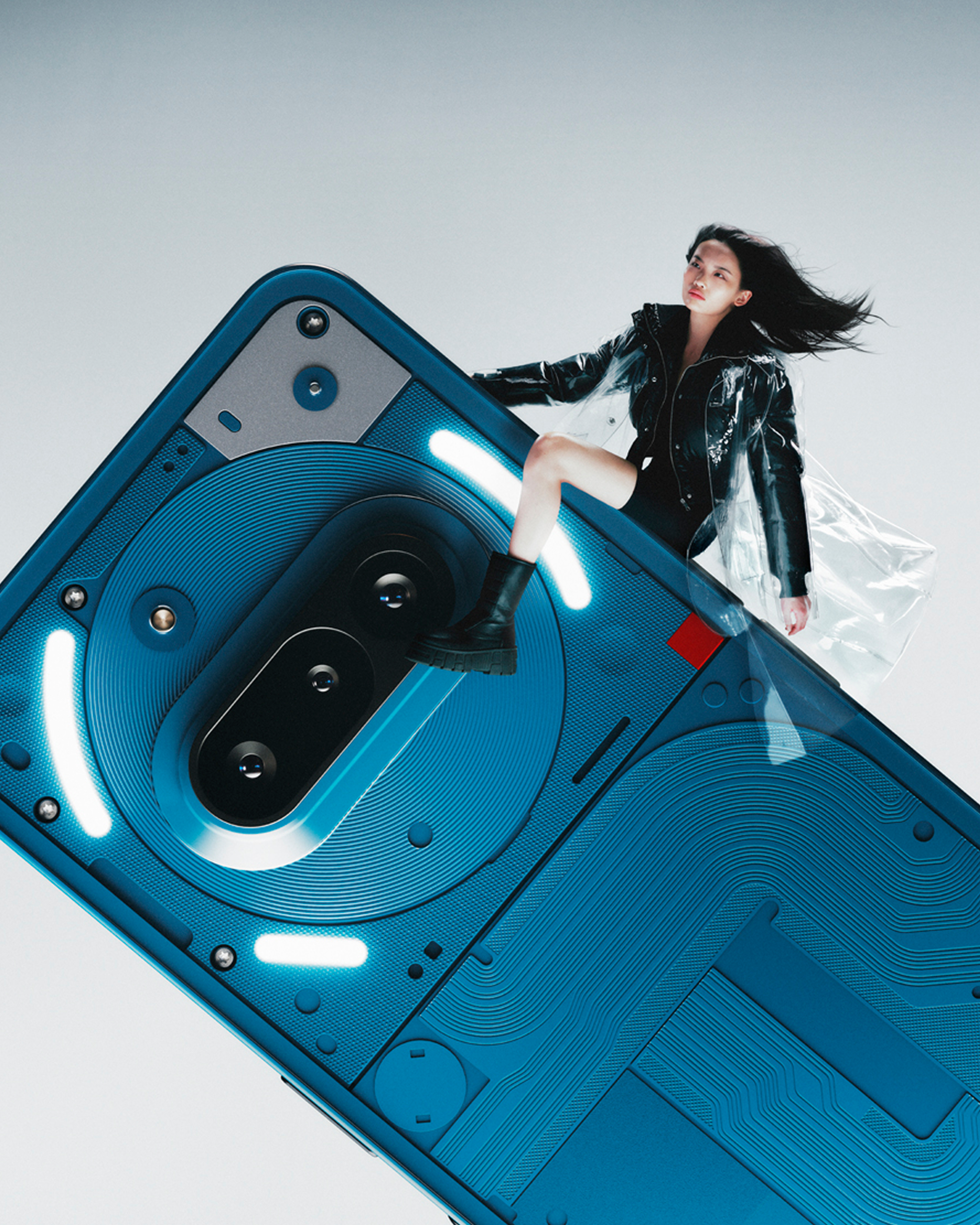 Frau in Lederjacke sitzt auf einem blauen Telefon. Telefonrückseite mit Kamera und Lichtern.