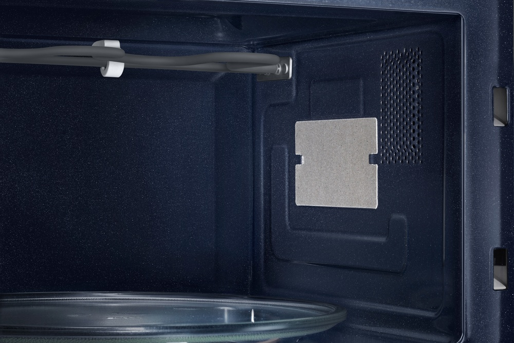 Primer plano del interior del microondas, mostrando el elemento calefactor, una placa metálica y una placa de vidrio.