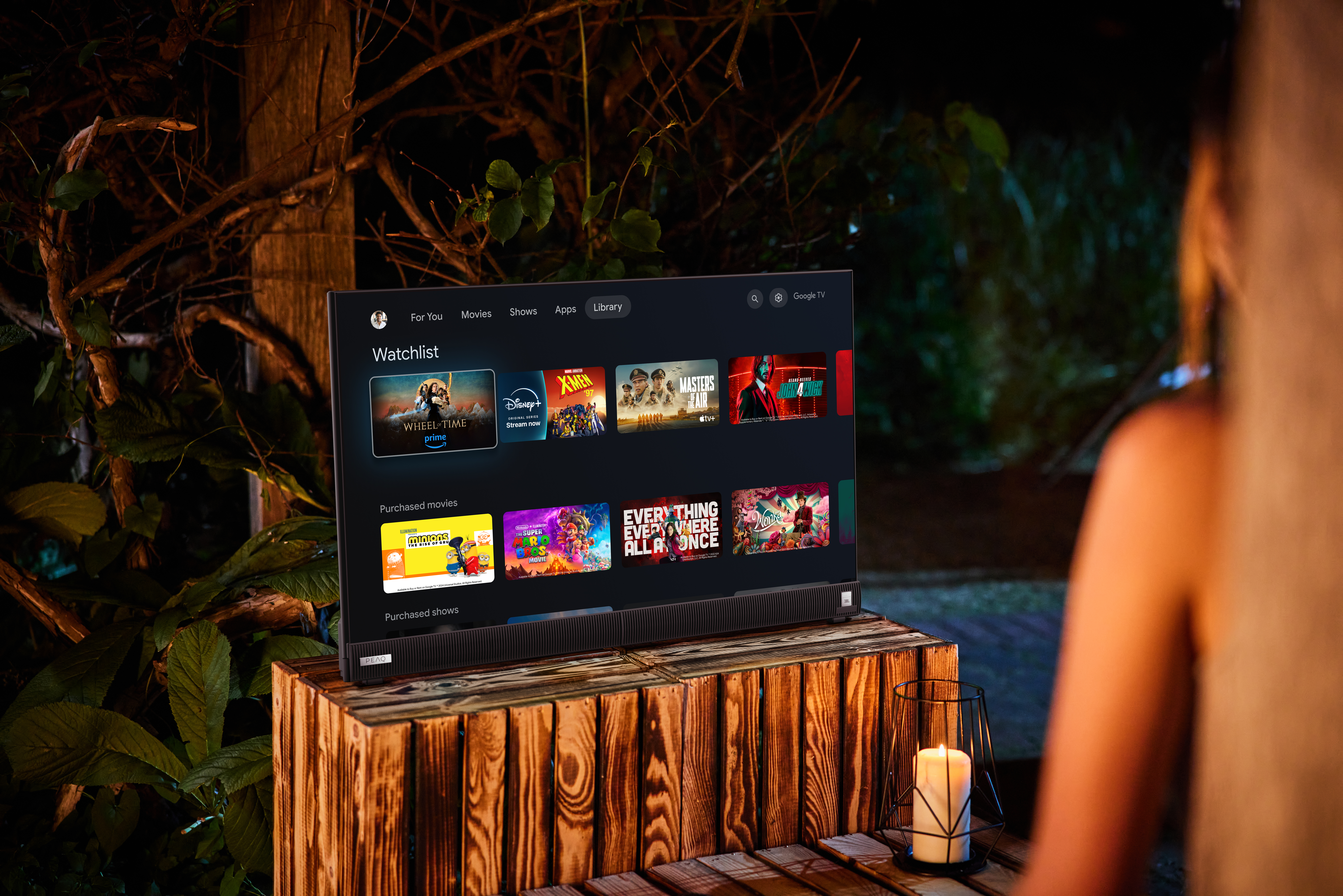Eine Frau hält im Freien einen Fernseher, der eine Streaming-Dienst-Oberfläche zeigt.