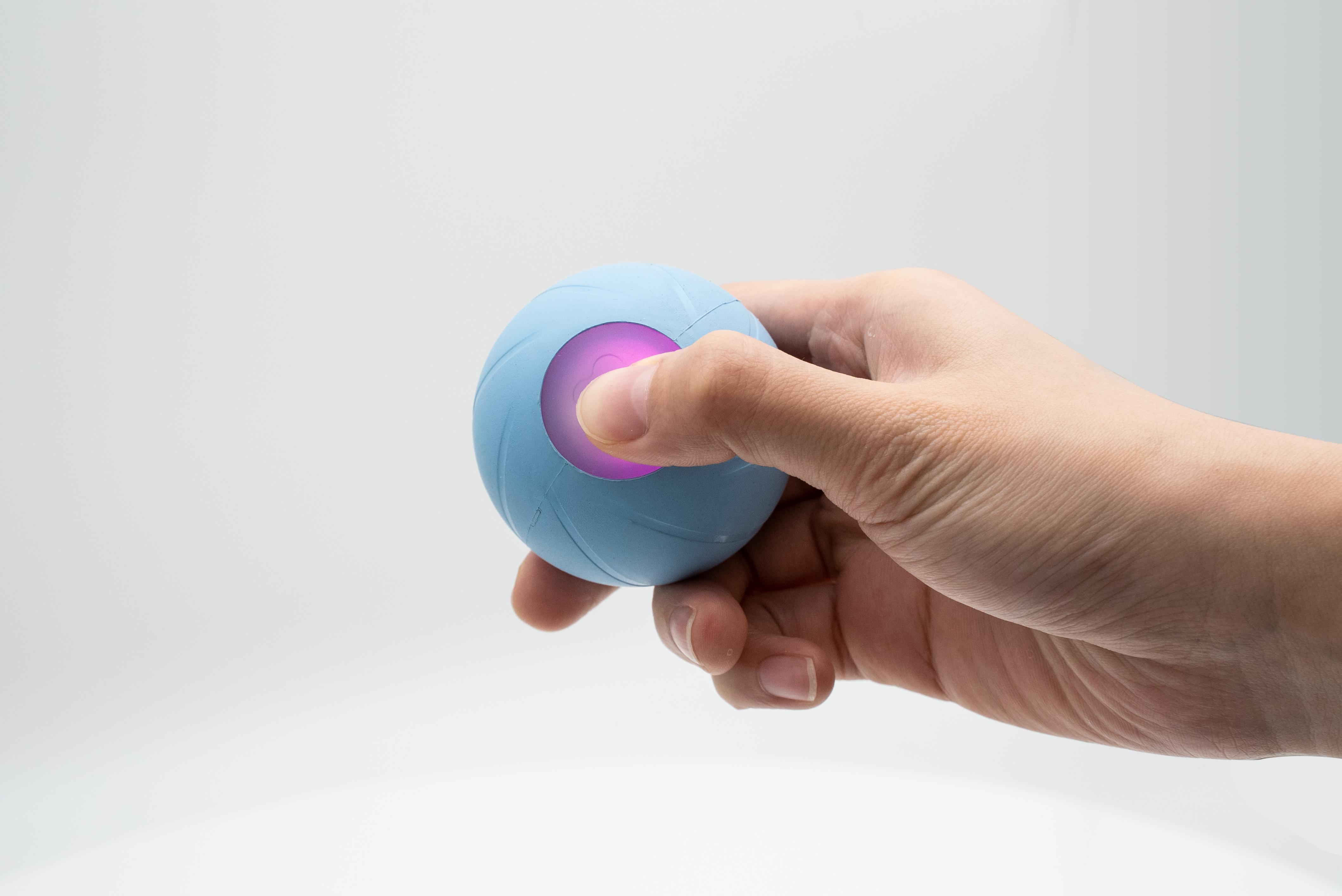 Die Hand einer Person, die einen hellblauen Ball mit einem pinkfarbenen Licht hält.