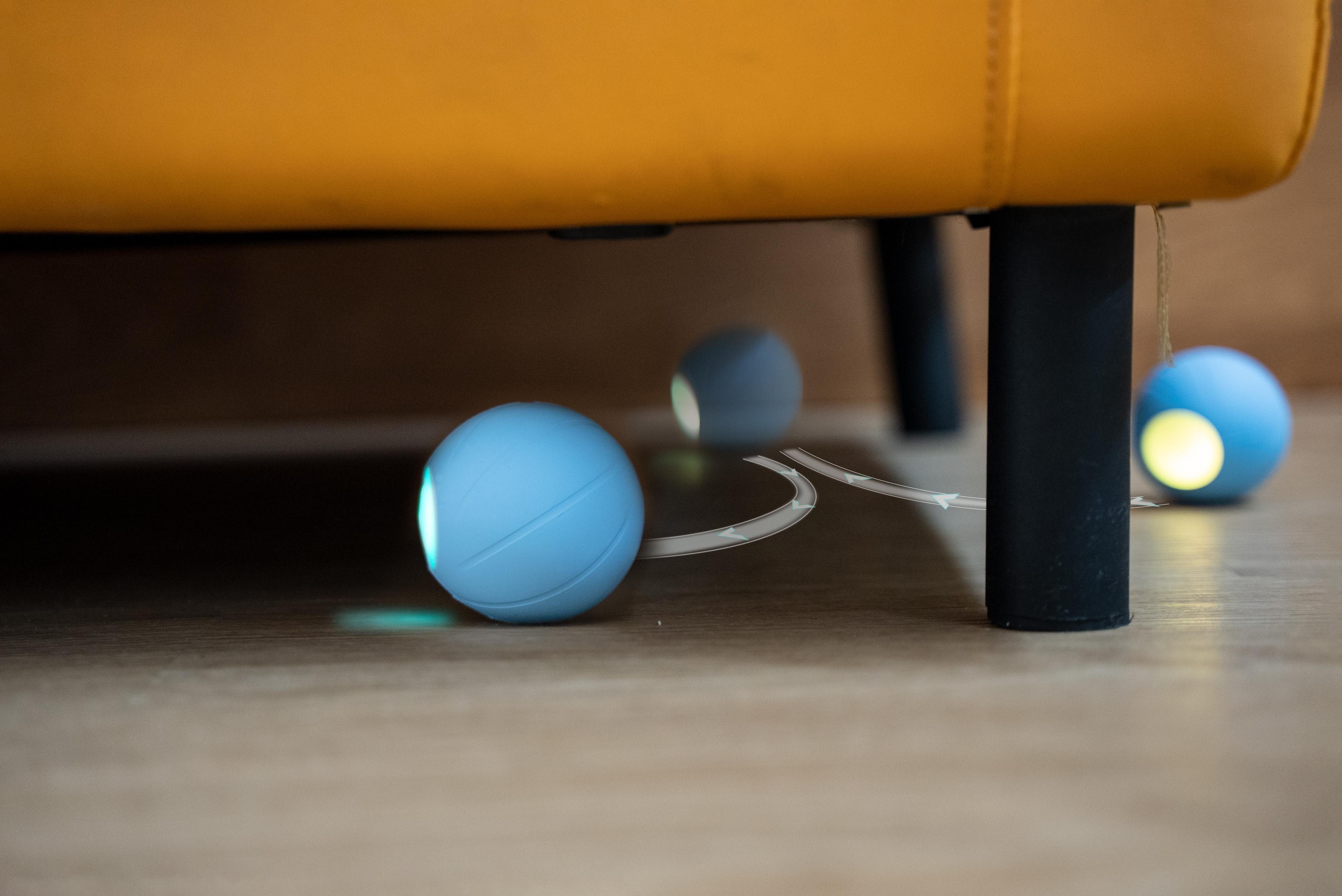 Drei hellblaue Bälle liegen unter einem gelben Sofa, wobei Licht von ihnen ausgeht.