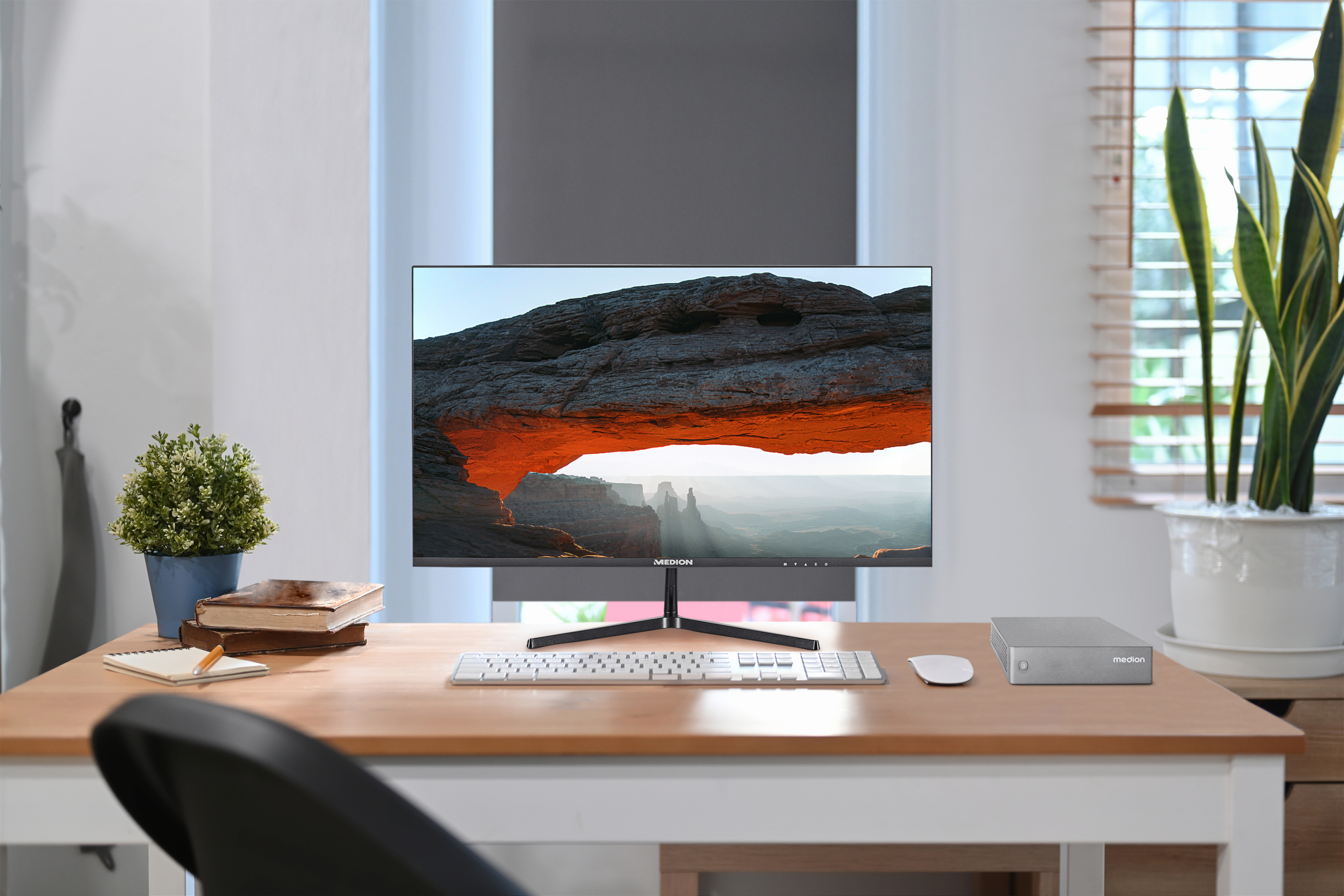 Bureau avec moniteur, clavier, souris, appareil Medion et plante. Fenêtre en arrière-plan.