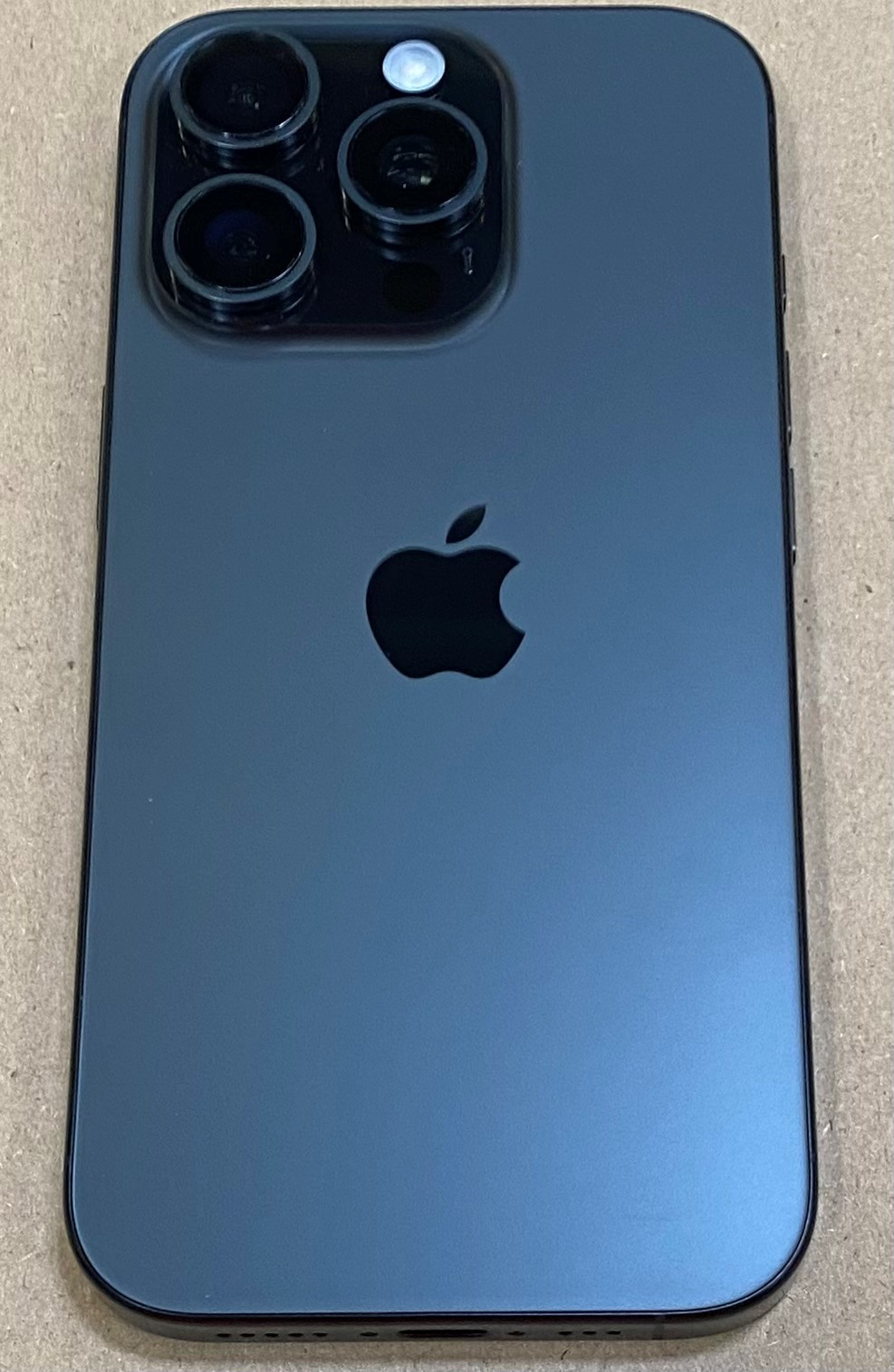 Tył ciemnoszarego iPhone'a z trzema obiektywami aparatu i logo Apple.