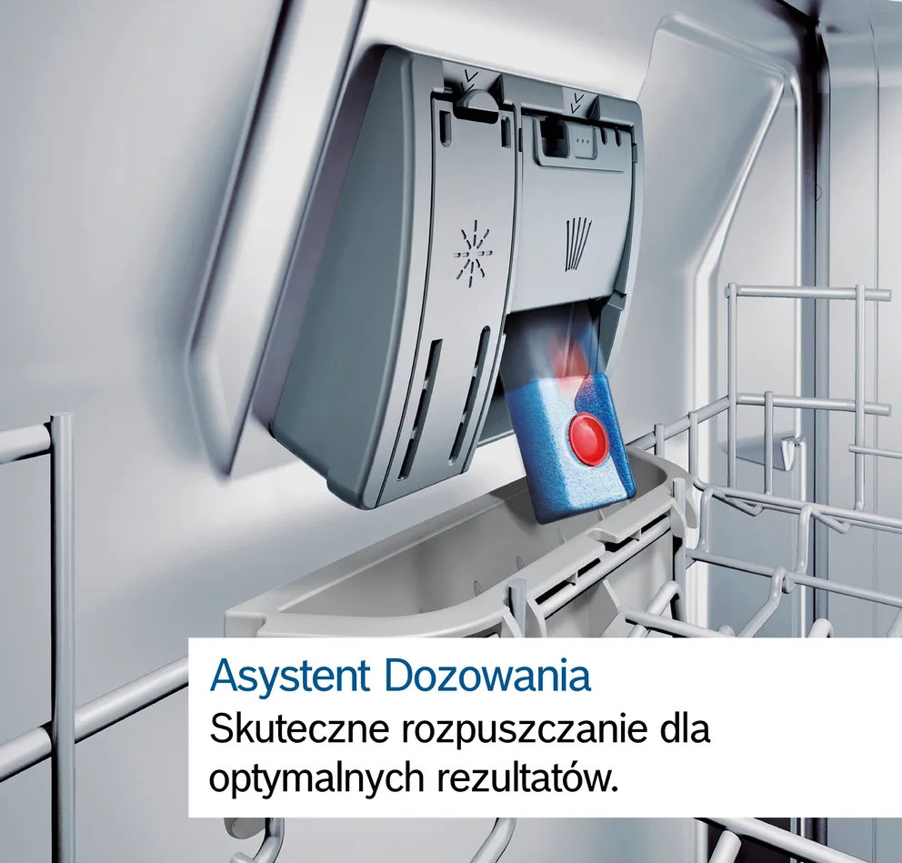 Wnętrze zmywarki. Dozownik detergentu z niebieską i czerwoną tabletką. Srebrzysty metal wewnątrz maszyny.