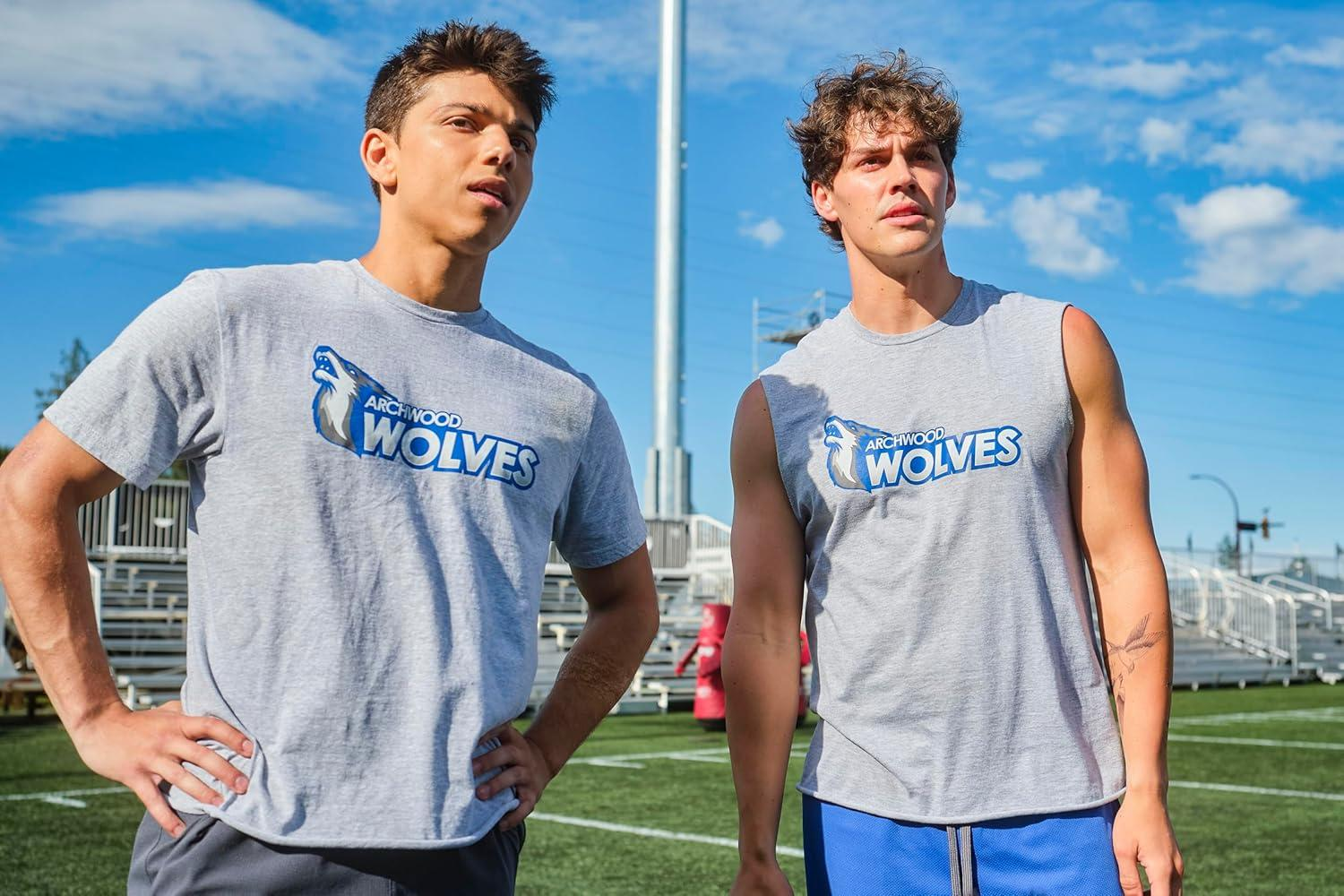 Zwei junge Männer in grauen Archwood Wolves Shirts stehen auf einem Feld.