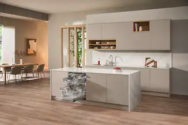 Merkezi bir ada ve açık bir bulaşık makinesi bulunan bir mutfak. Sandalyeler ve yeşil bitkilerle masa.