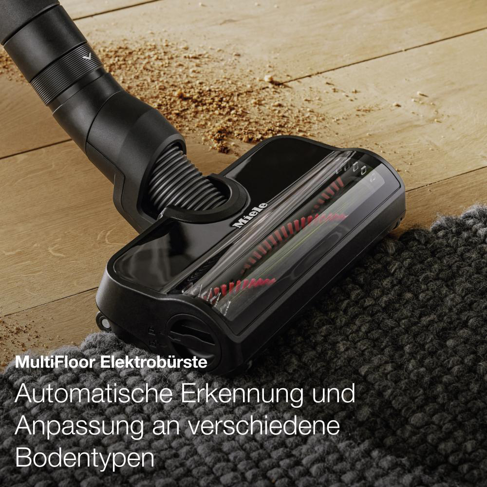Staubsaugerbürste auf einem Teppich. Schwarz und grau. Holzfußboden.