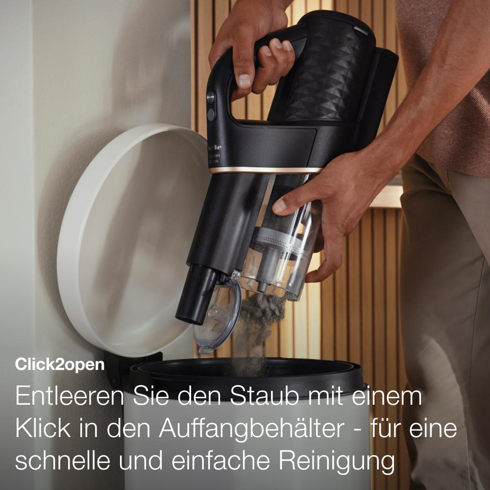 Staubsauger entleert sich in einen Mülleimer. Staub und Schmutz sichtbar.