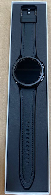 Czarny smartwatch ze skórzanym paskiem w białym pudełku. Tarcza zegarka jest czarna.