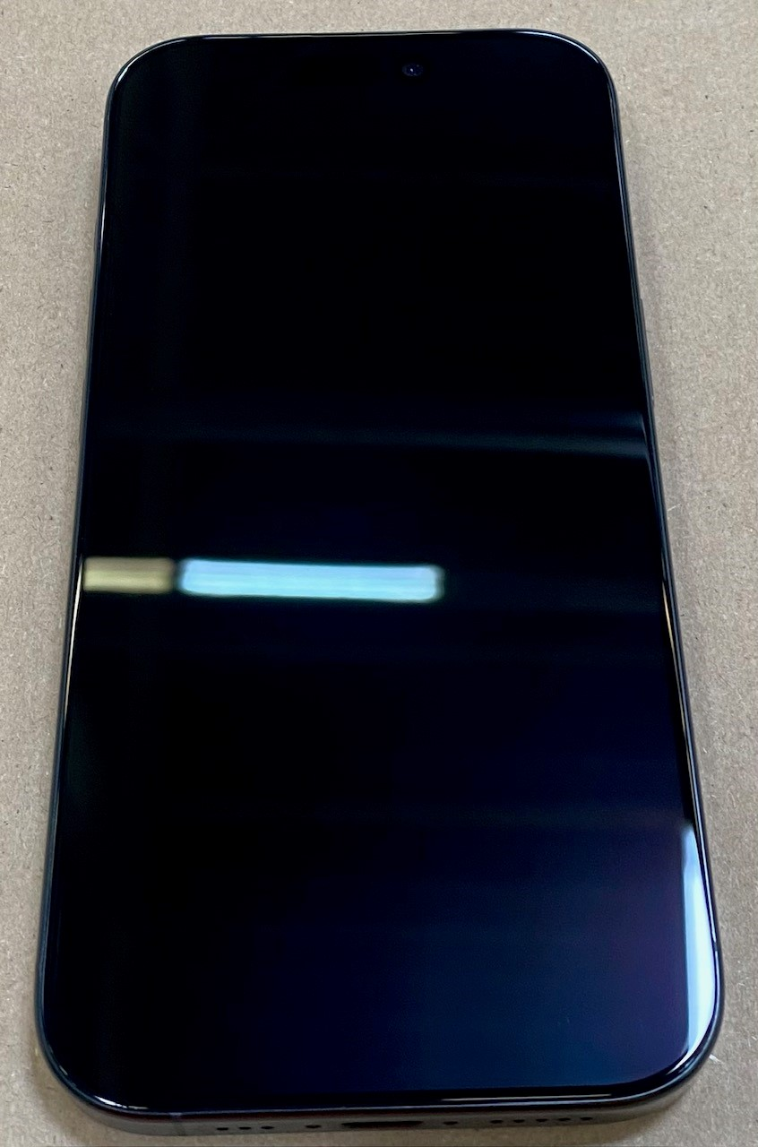 Czarny ekran iPhone'a, pokazujący odbicia. Telefon leży na jasnej powierzchni.