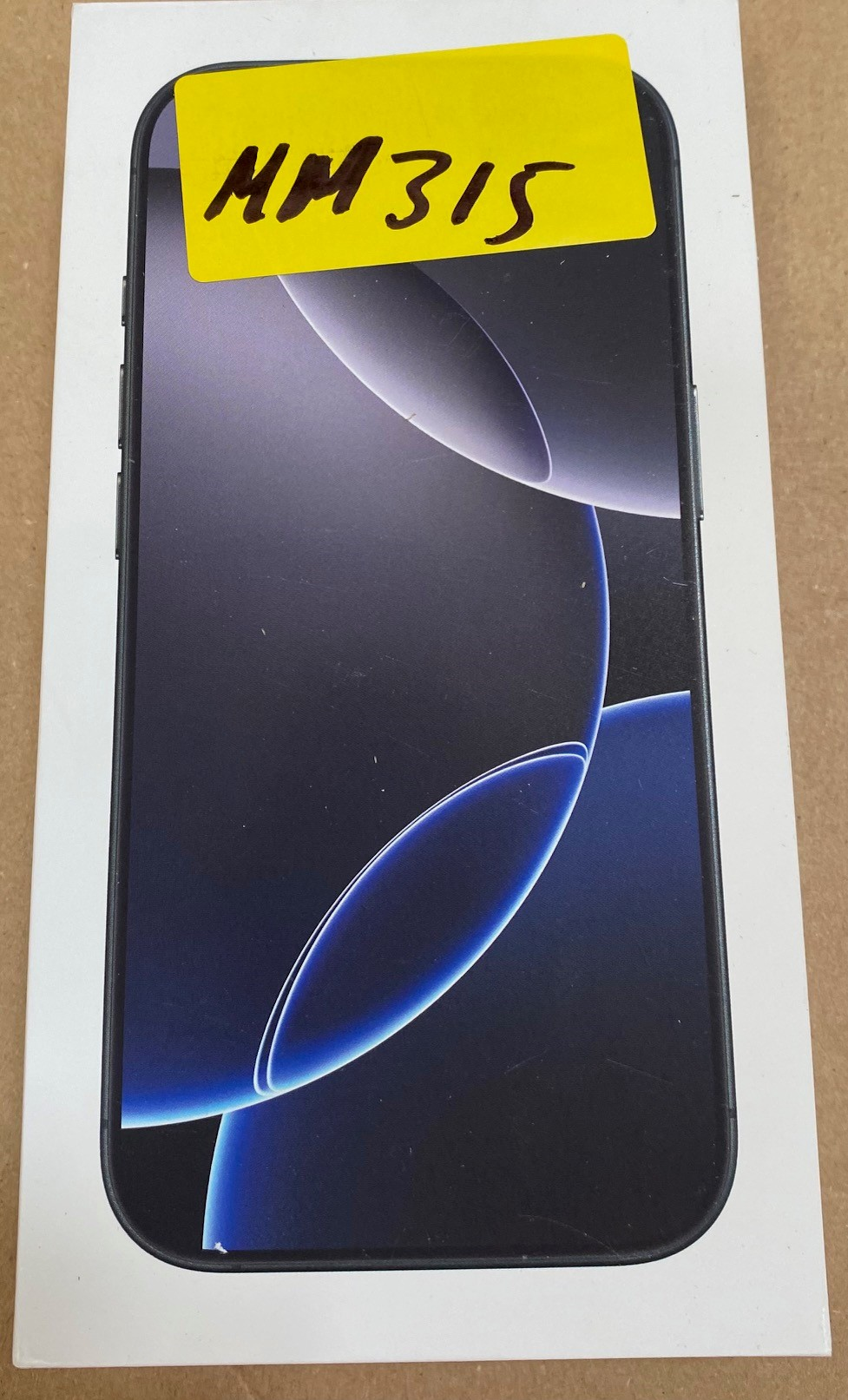 Pudełko iPhone'a z telefonem w środku, z żółtą naklejką z napisem MM 315.