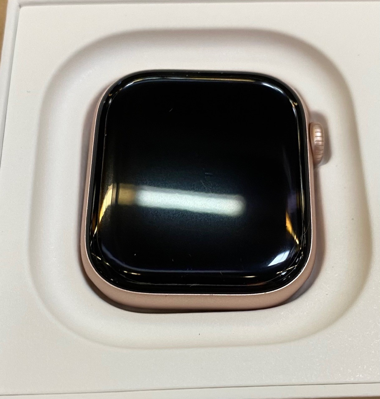 Zegarek Apple Watch w pudełku, z ekranem skierowanym w stronę kamery.