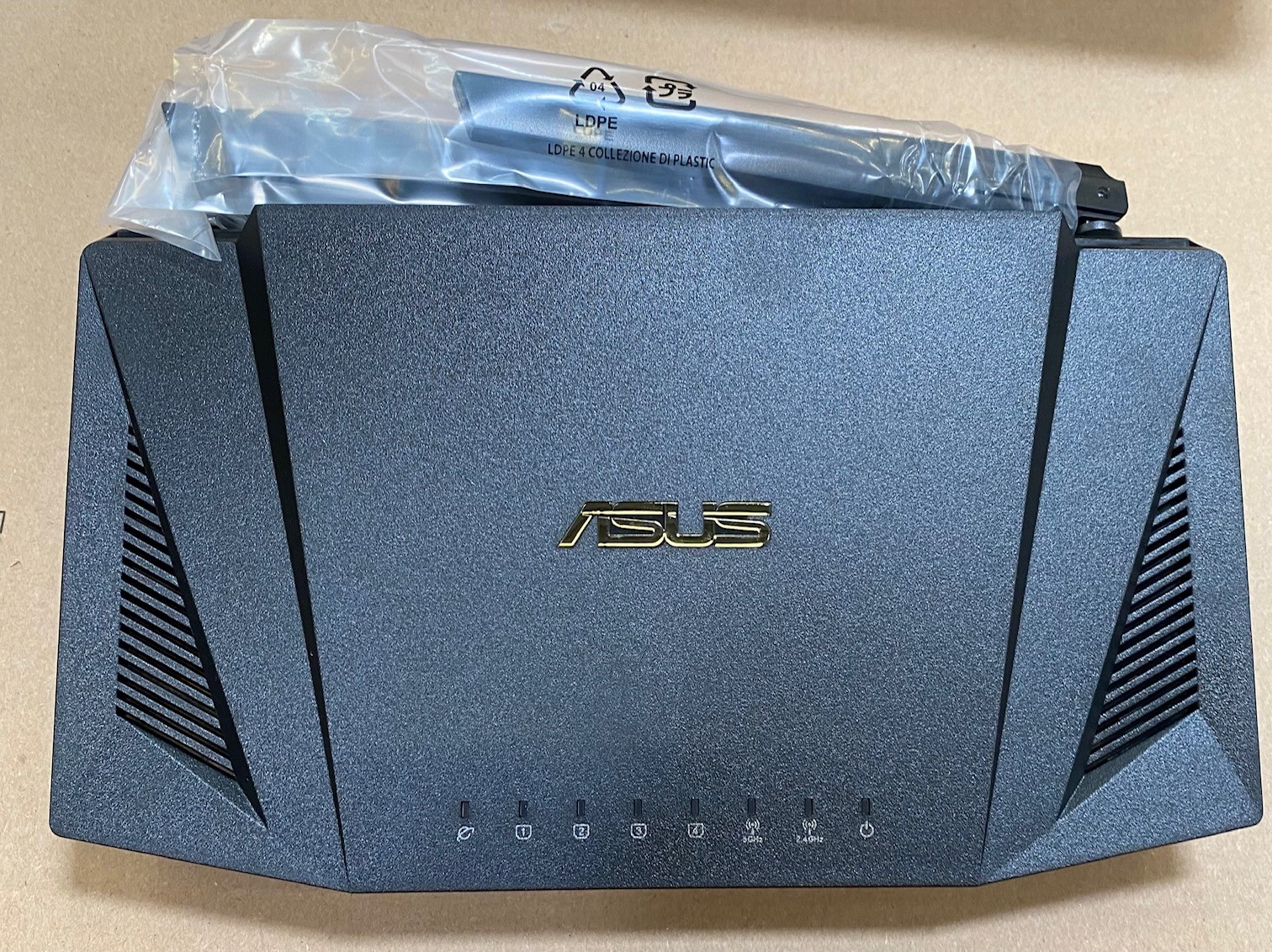 Czarny router ASUS z antenami i folią na górze.