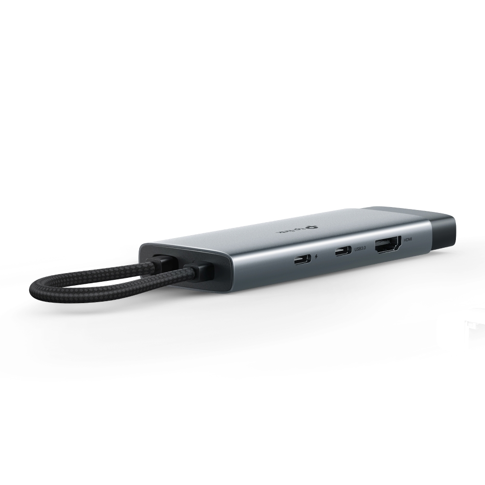 Siyah kablo döngüsüne sahip gümüş USB-C hub. Portlar: USB 3.0, HDMI ve şarj. Beyaz arka plan.