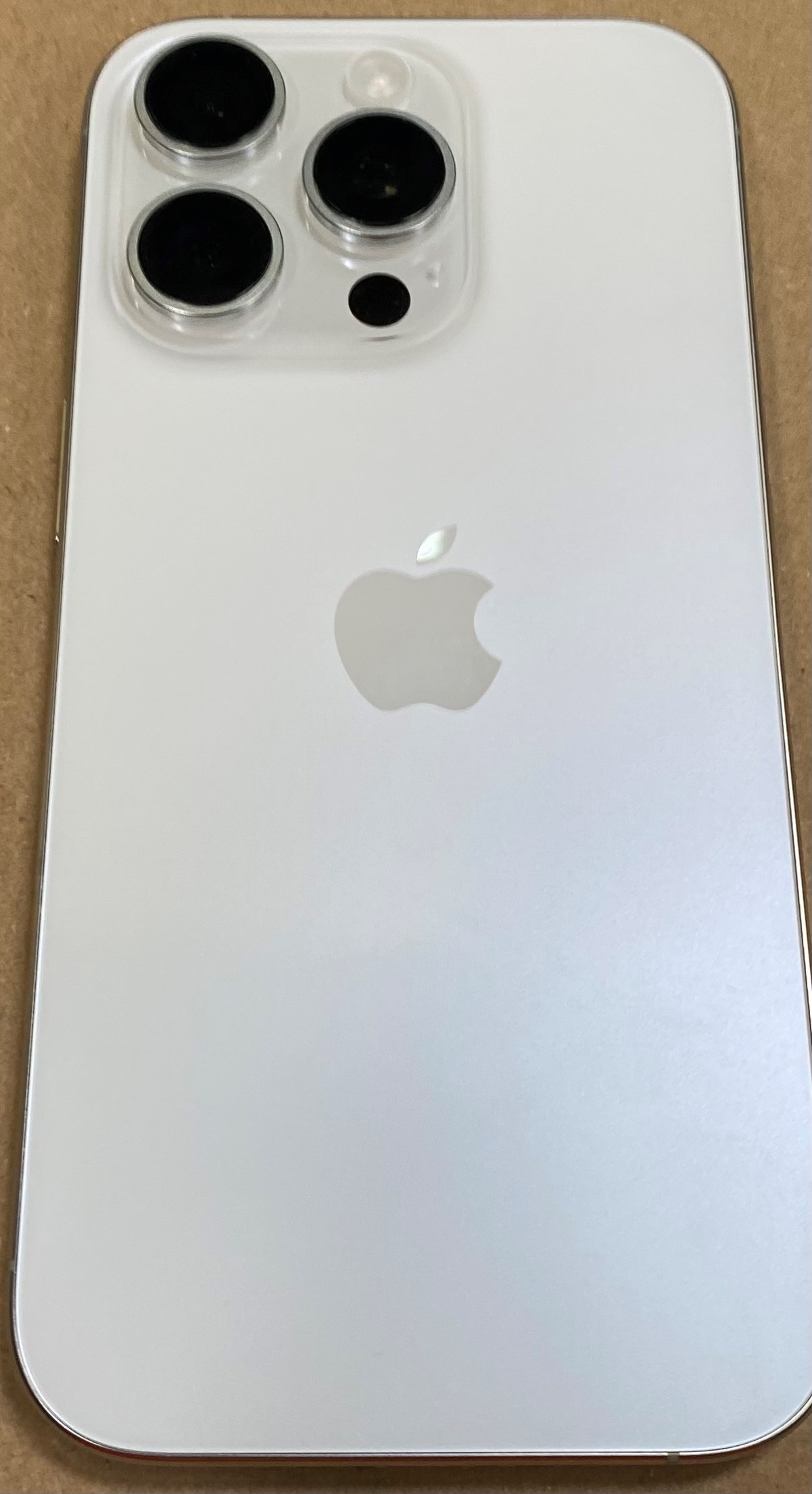 Tył białego iPhone'a z trzema obiektywami aparatu i logo Apple.