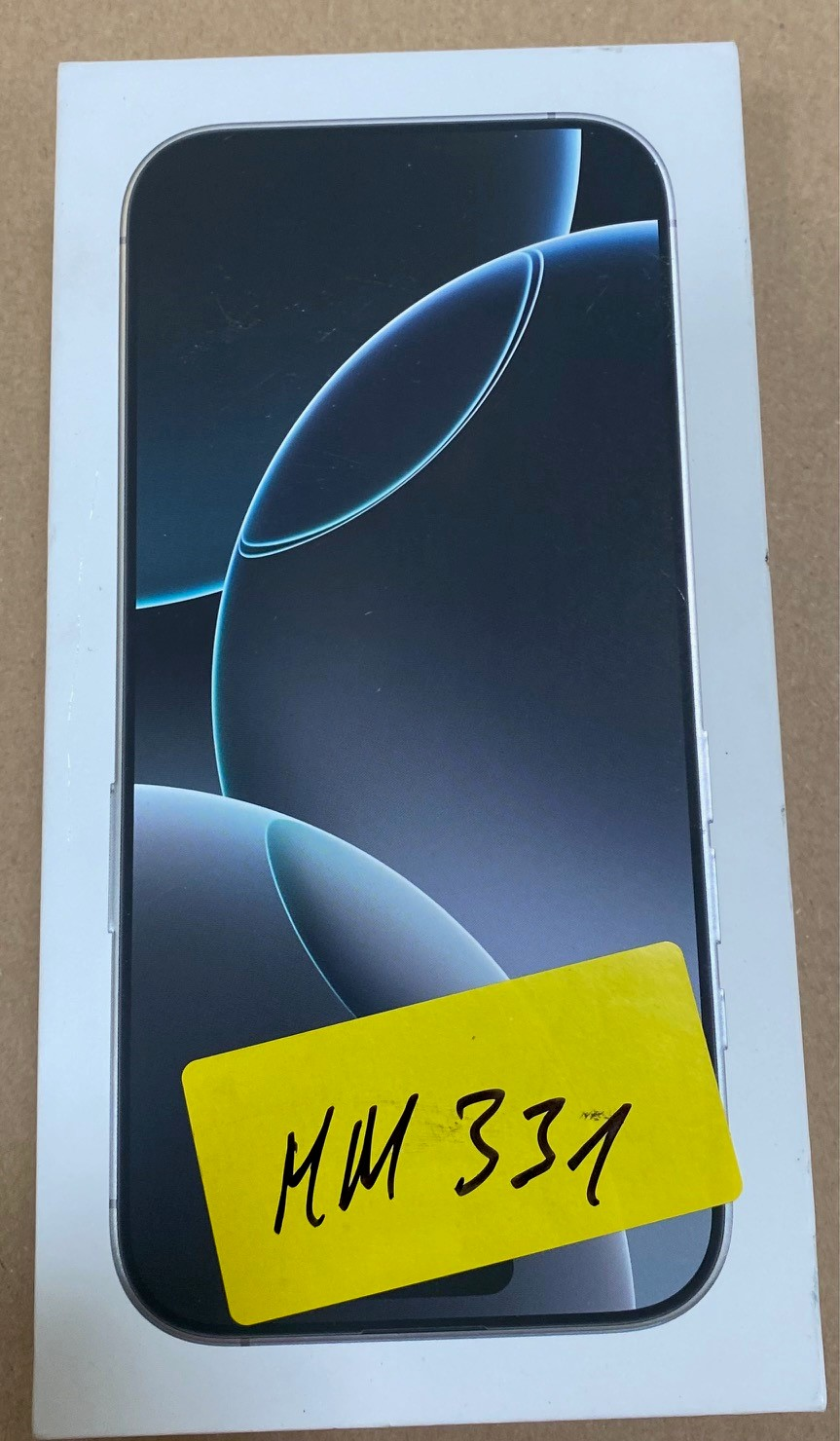 iPhone w pudełku z żółtą naklejką oznaczony 'MM 331'.
