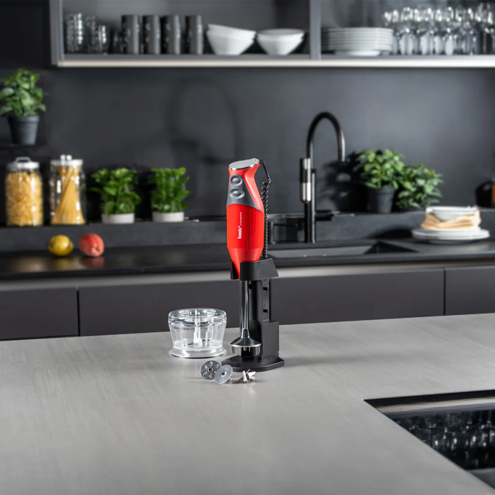 Mixeur plongeant rouge dans un cadre de cuisine, avec accessoires.