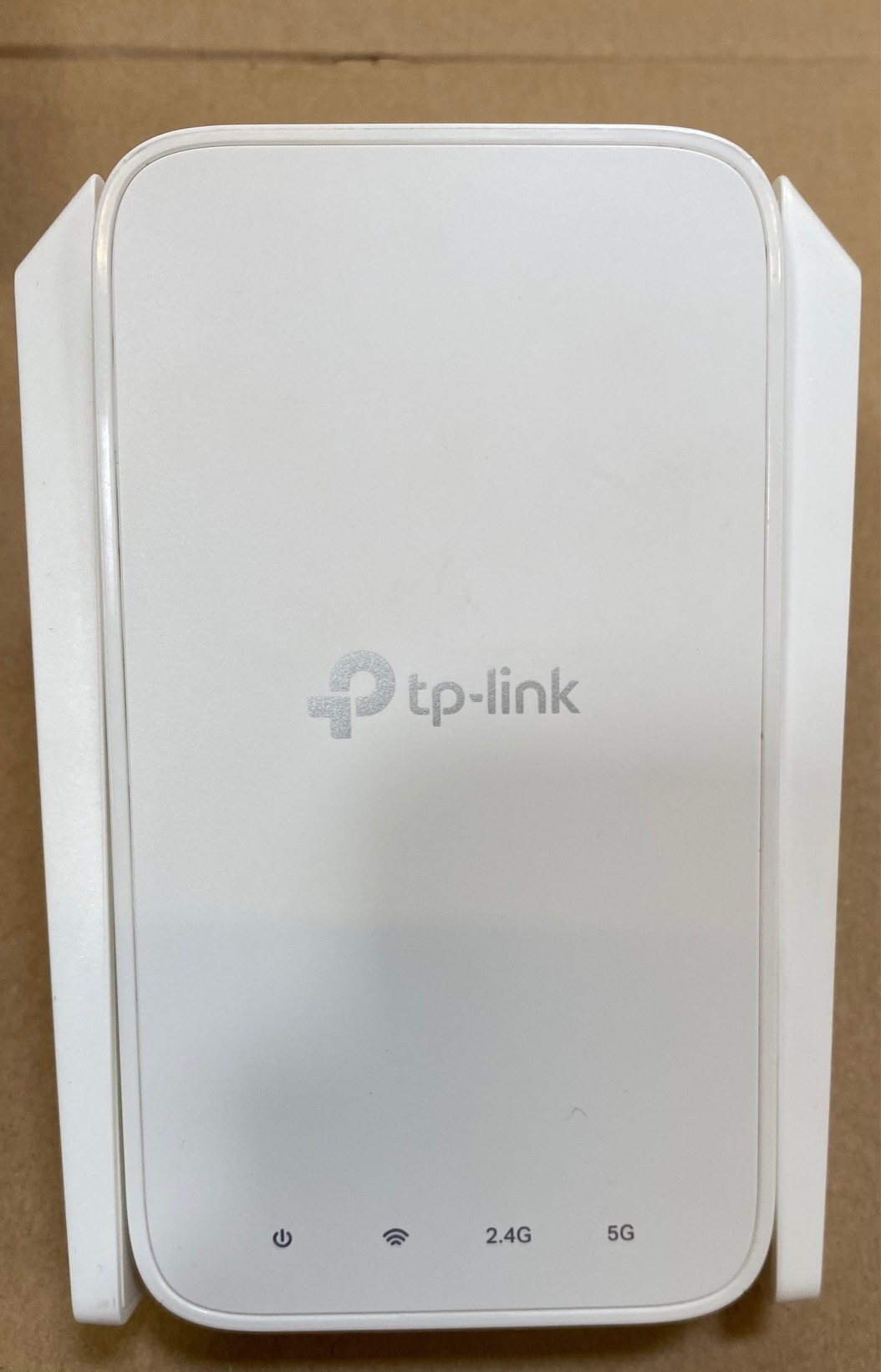 Biały wzmacniacz Wi-Fi Mesh TP-Link. Widoczny tekst i światła. Szare tło.