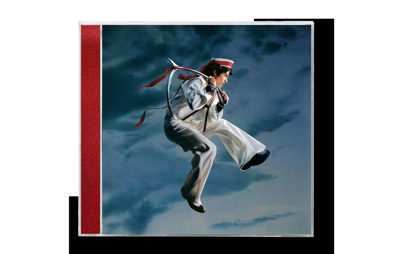 Albumcover. Ein Mann im Matrosenanzug schwebt in der Luft und hält einen silbernen Reifen.