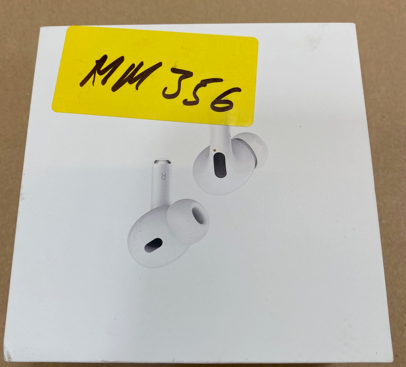 Białe AirPods Pro w pudełku z żółtą etykietą z napisem MM 356 z przodu.