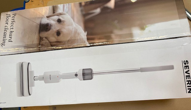 Pudełko przedstawia białego psa i myjkę do podłóg. Myjka jest biało-srebrna, z marką SEVERIN.