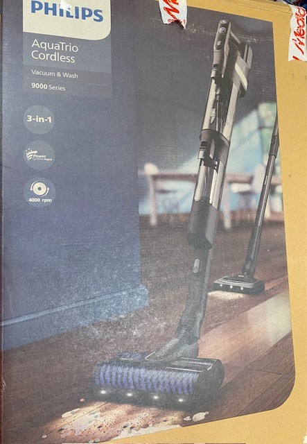 Zapakowany odkurzacz bezprzewodowy Philips AquaTrio. Obraz przedstawia odkurzacz na drewnianej podłodze z kroplami wody.