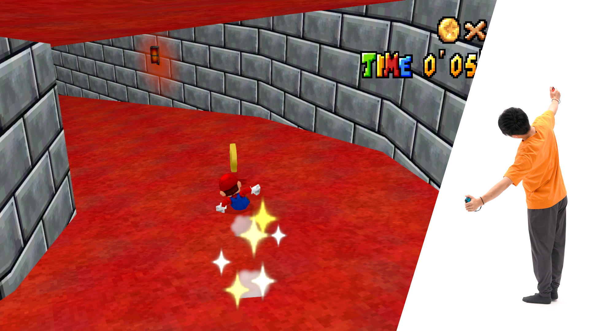 Mario in einem roten Lava-Raum, neben einer Person, die einen Controller hält. Das Spiel zeigt einen Timer und ein gelbes Ausrufezeichen.