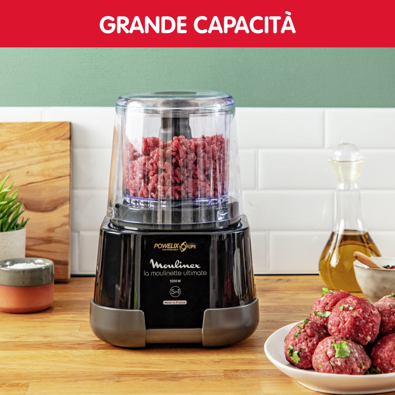 Robot da cucina nero con carne tritata. Polpette e ingredienti sul bancone di legno.