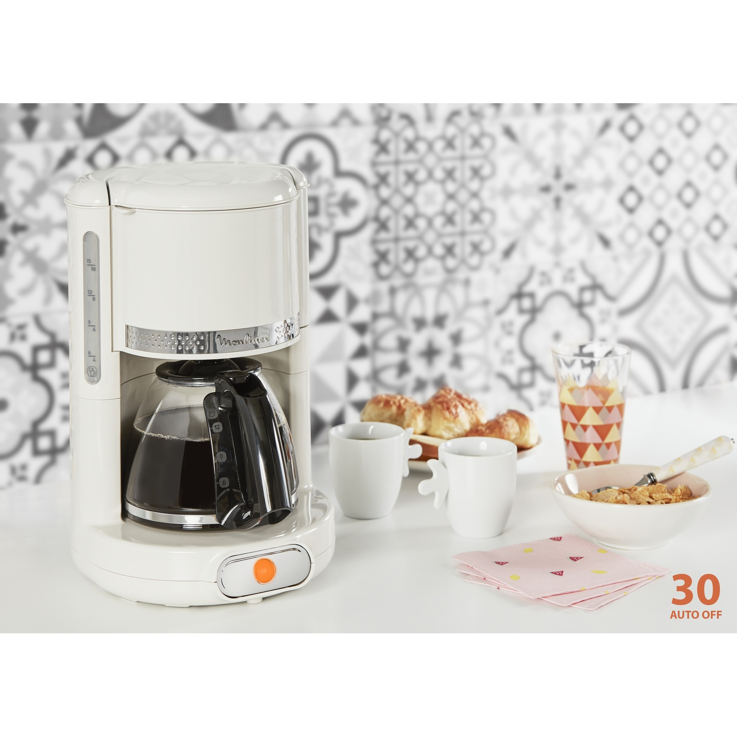 Una caffettiera bianca con caffè nella sua caraffa. Due tazze, pasticcini e succo sul tavolo.