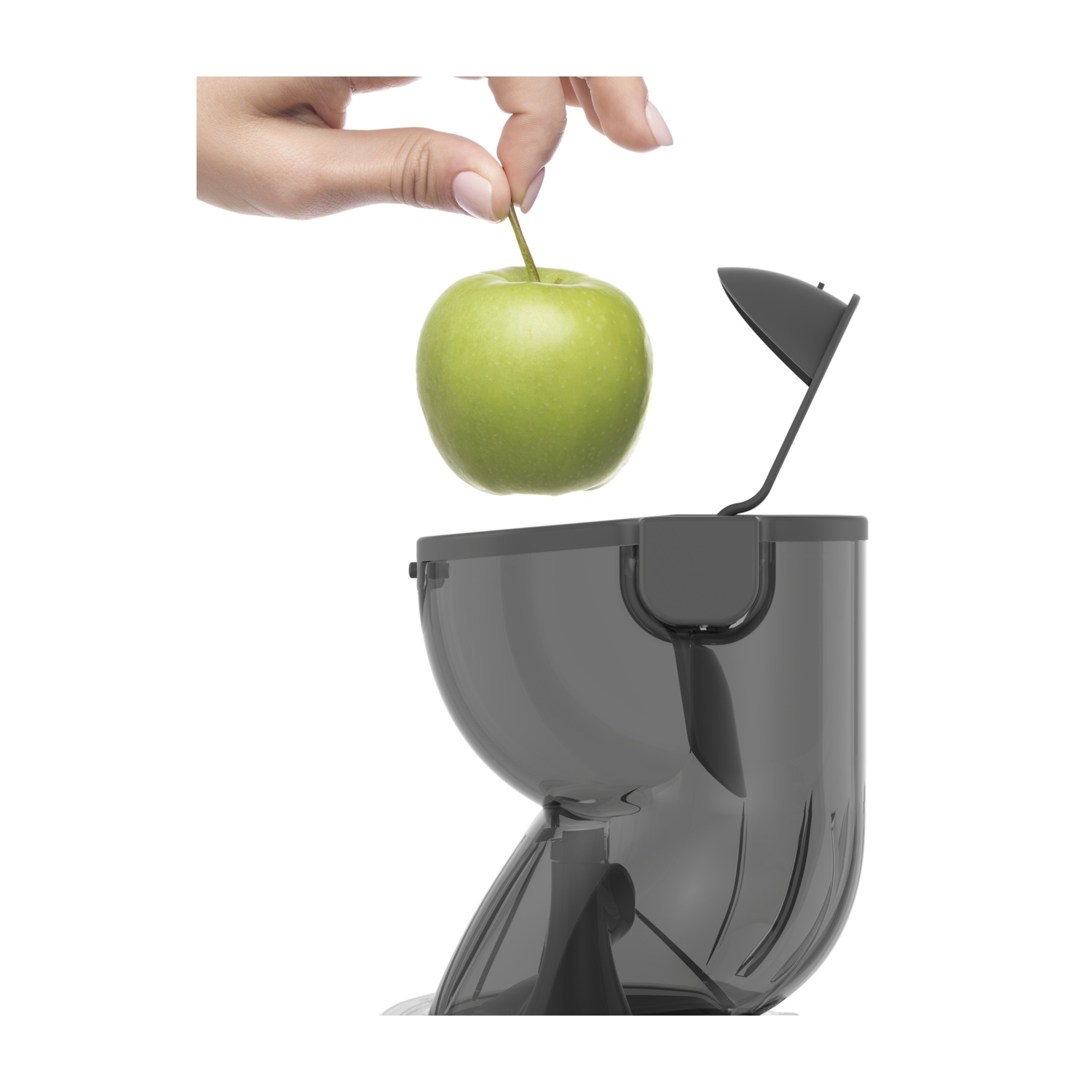 Mano che tiene una mela verde sopra un estrattore di succo grigio scuro.