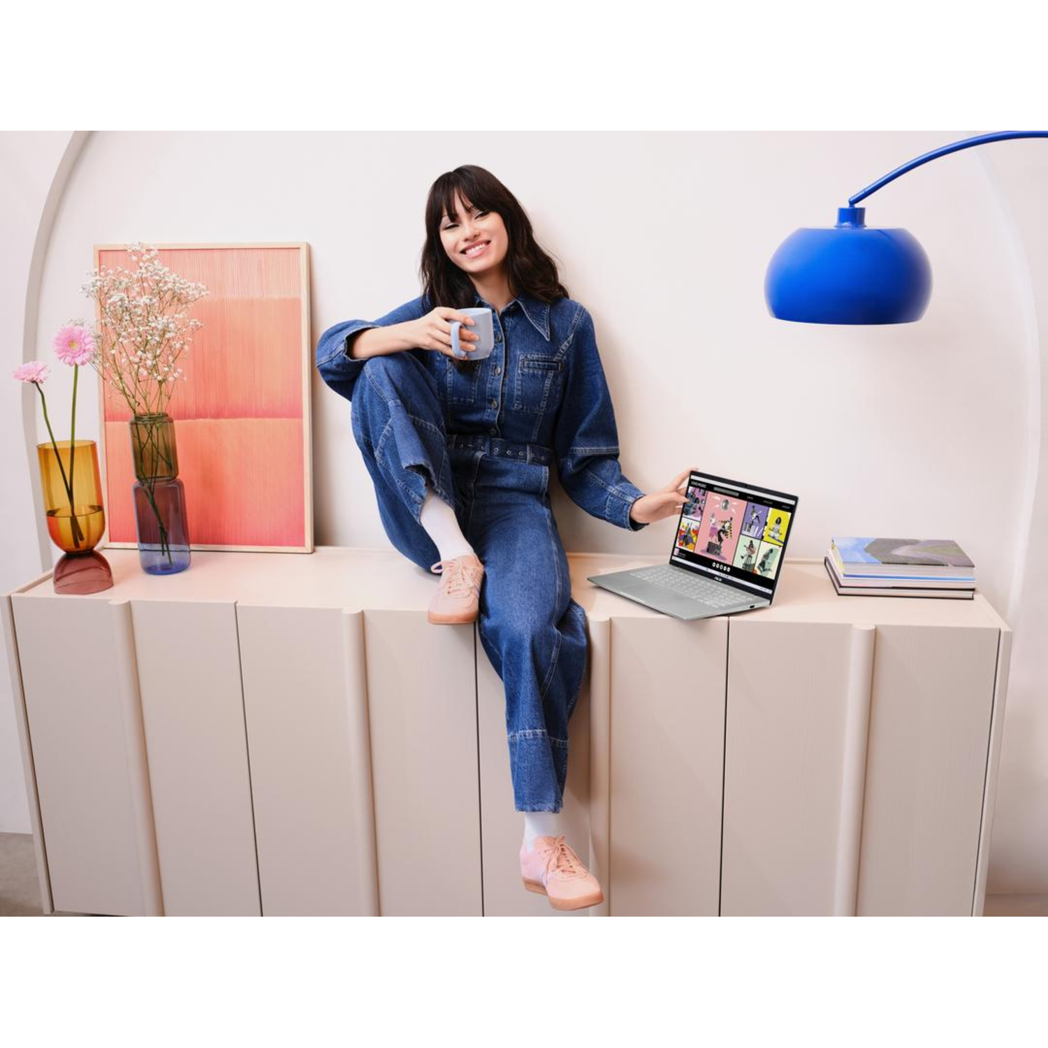 Vrouw zittend, laptop gebruikend, een kopje koffie en decor, heldere achtergrond.