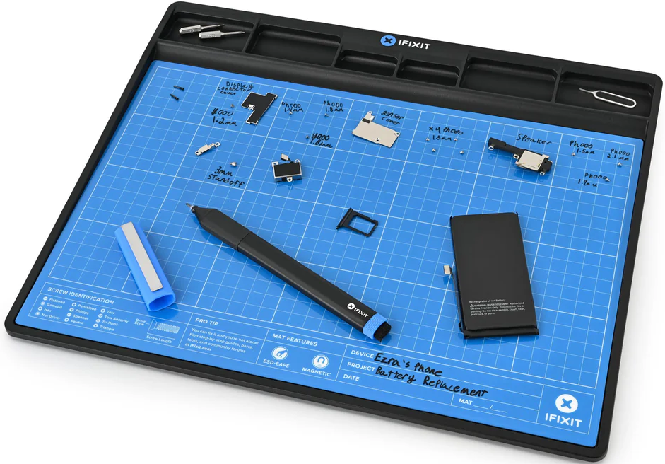 Blaue Matte mit Telefonteilen, Werkzeugen, Akku und Stift. Text auf der Matte: Battery Replacement. Schwarzer Rand.